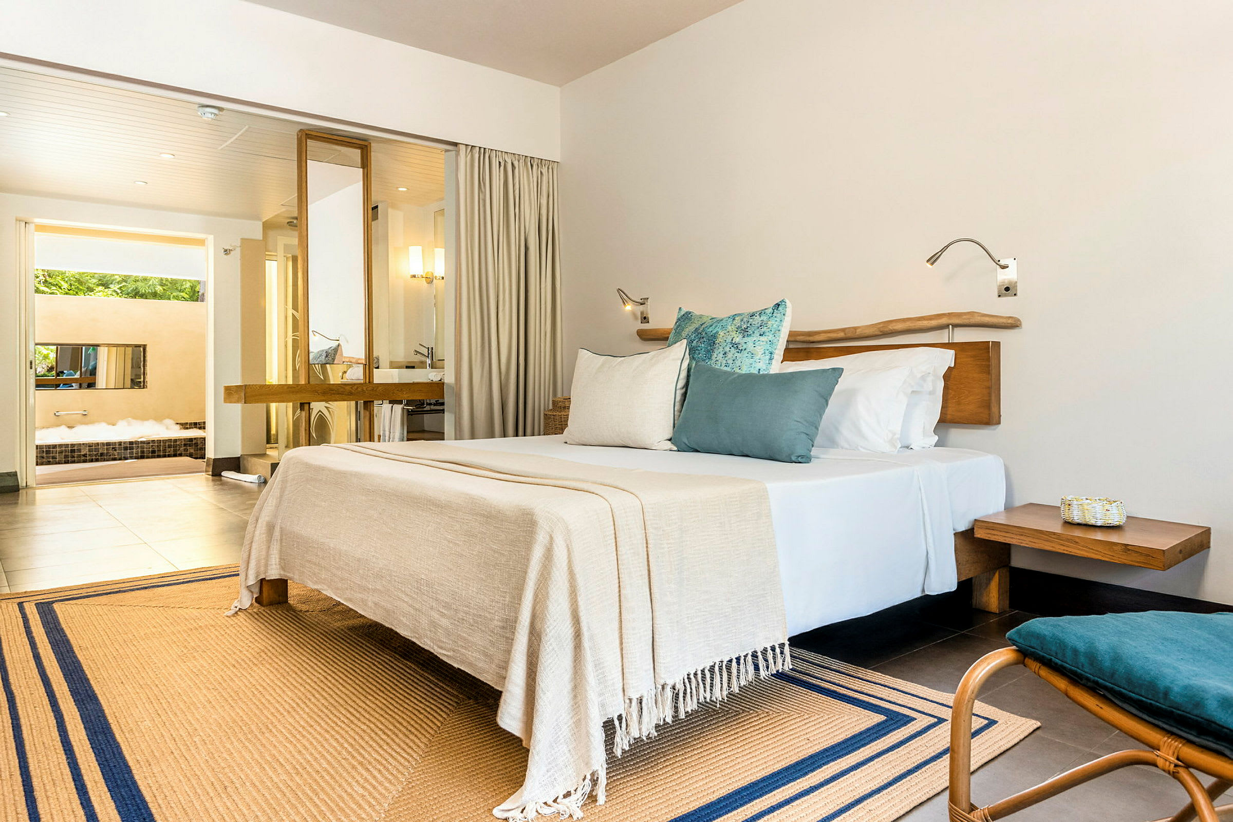 Ett modernt hotellrum med en stor säng, kuddar och ingång till badrum med jacuzzi. (AI-genererad text)