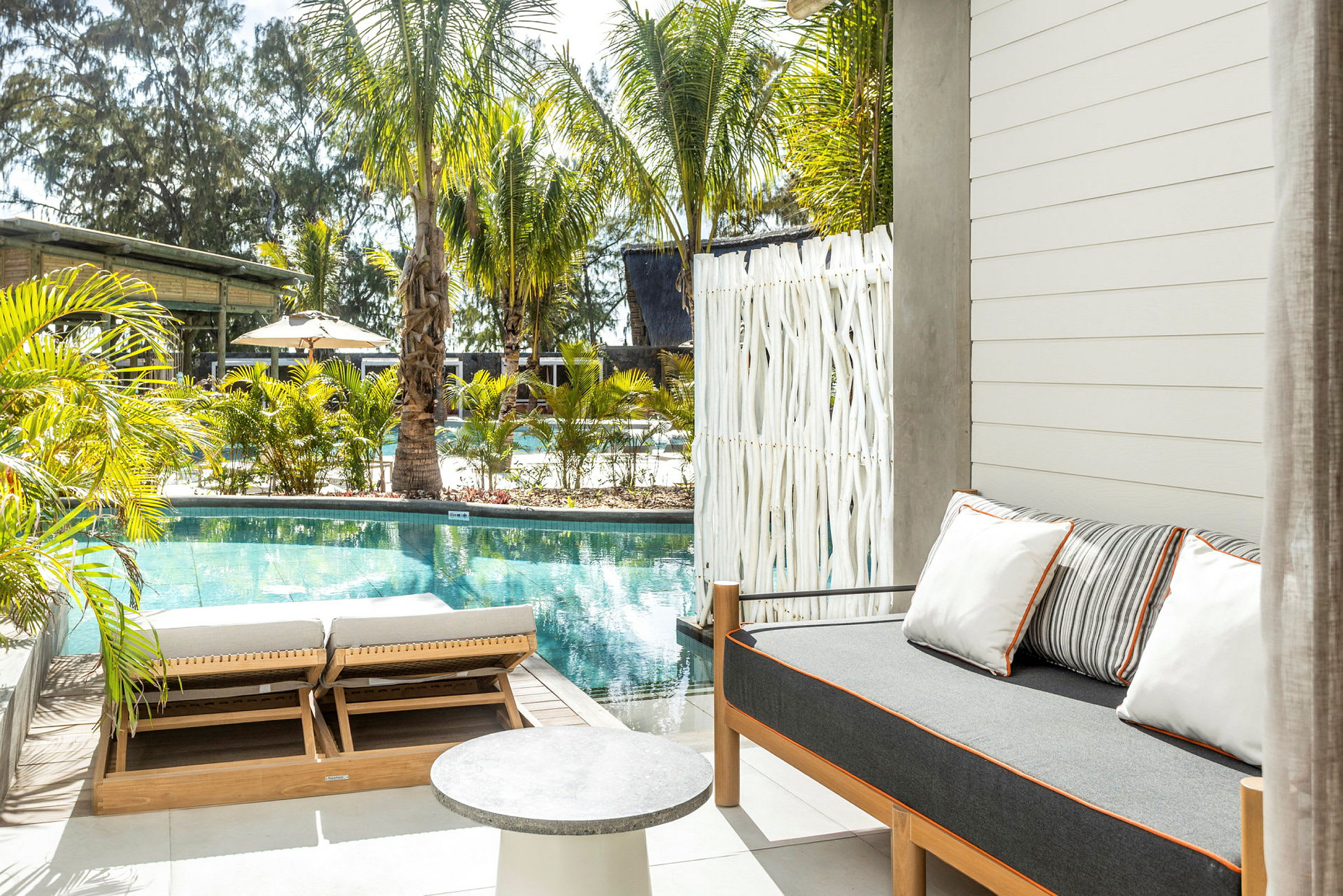 Utomhusområde med pool, solstolar och en soffa med kuddar. (AI-genererad text)
