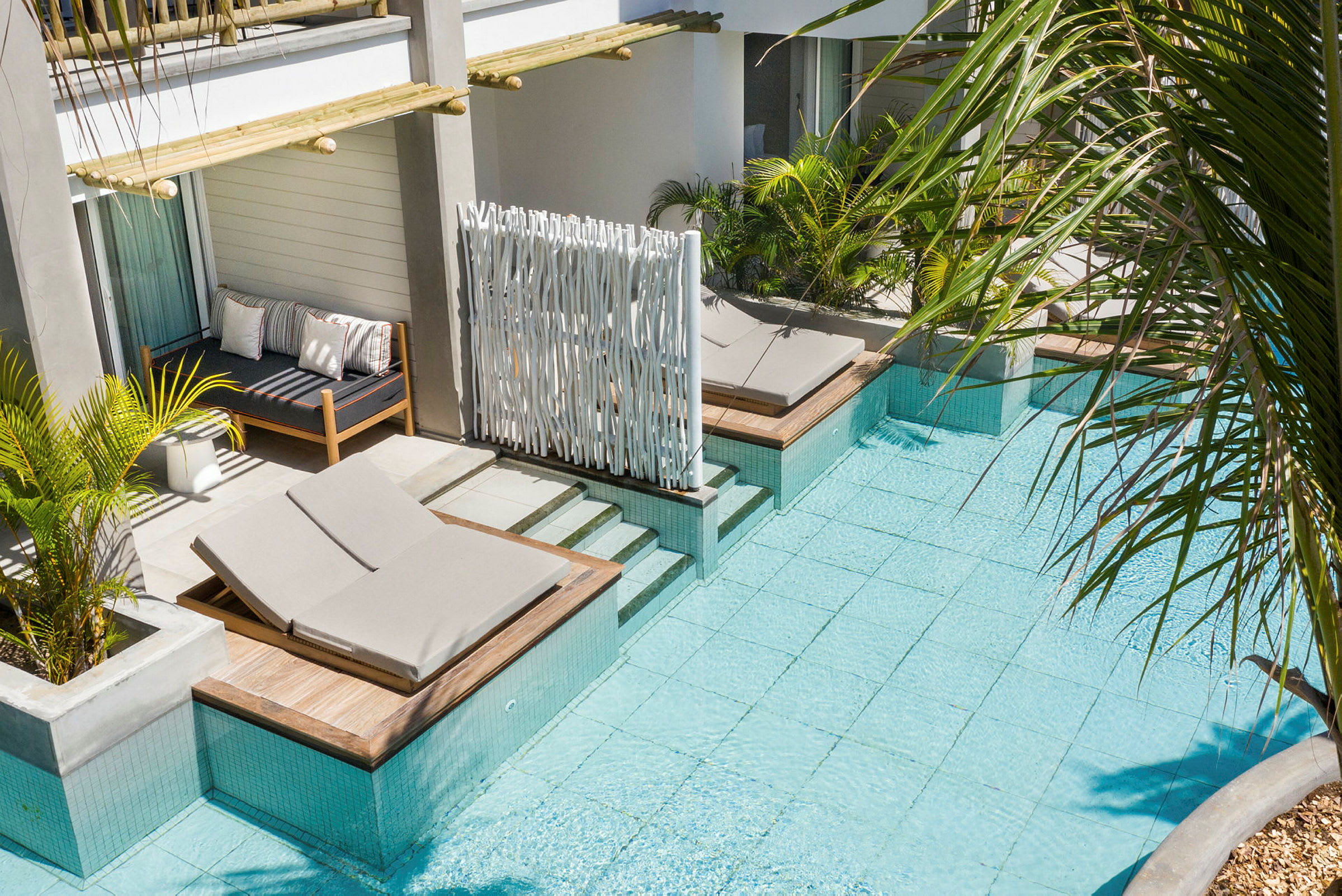 Hotellrum med utsikt över en pool, solstolar och grön växtlighet. (AI-genererad text)