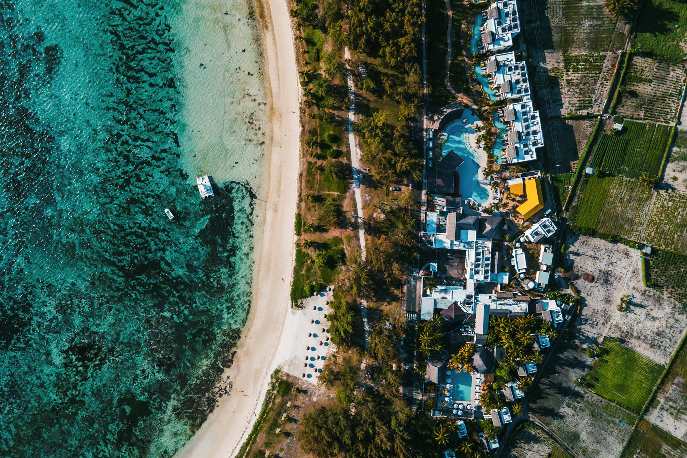 En flygbild över en strand vid havet, med byggnader och grönområden intill. (AI-genererad text)