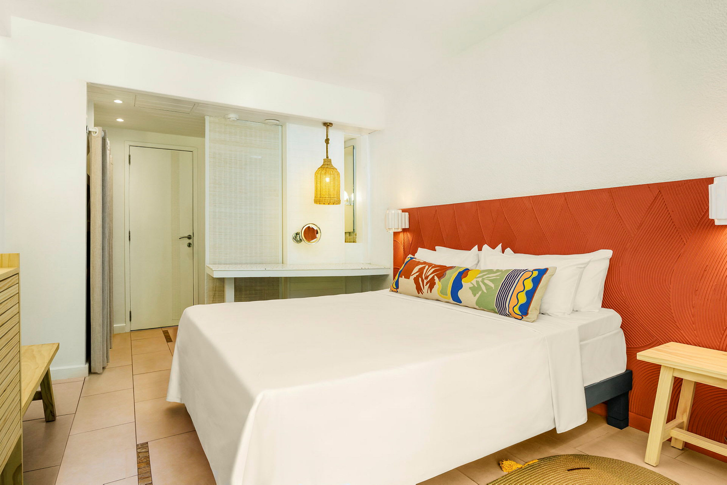 Hotellrum med en dubbelsäng, färgglad kudde och en orange sänggavel. (AI-genererad text)