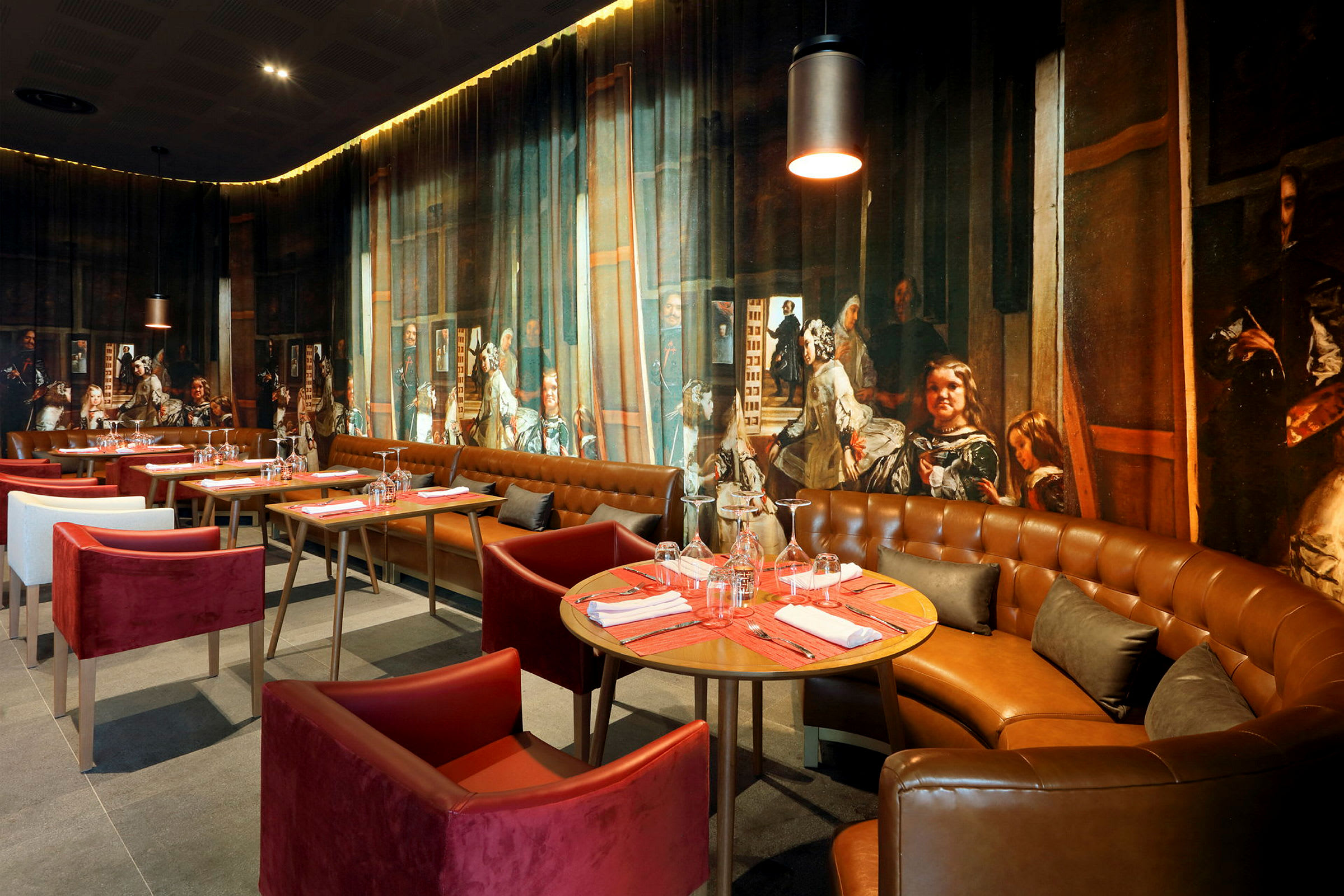 En restauranginteriör med matbord och stolar, elegant inredning samt en väggdekoration föreställande en detaljrik målning. (AI-genererad text)