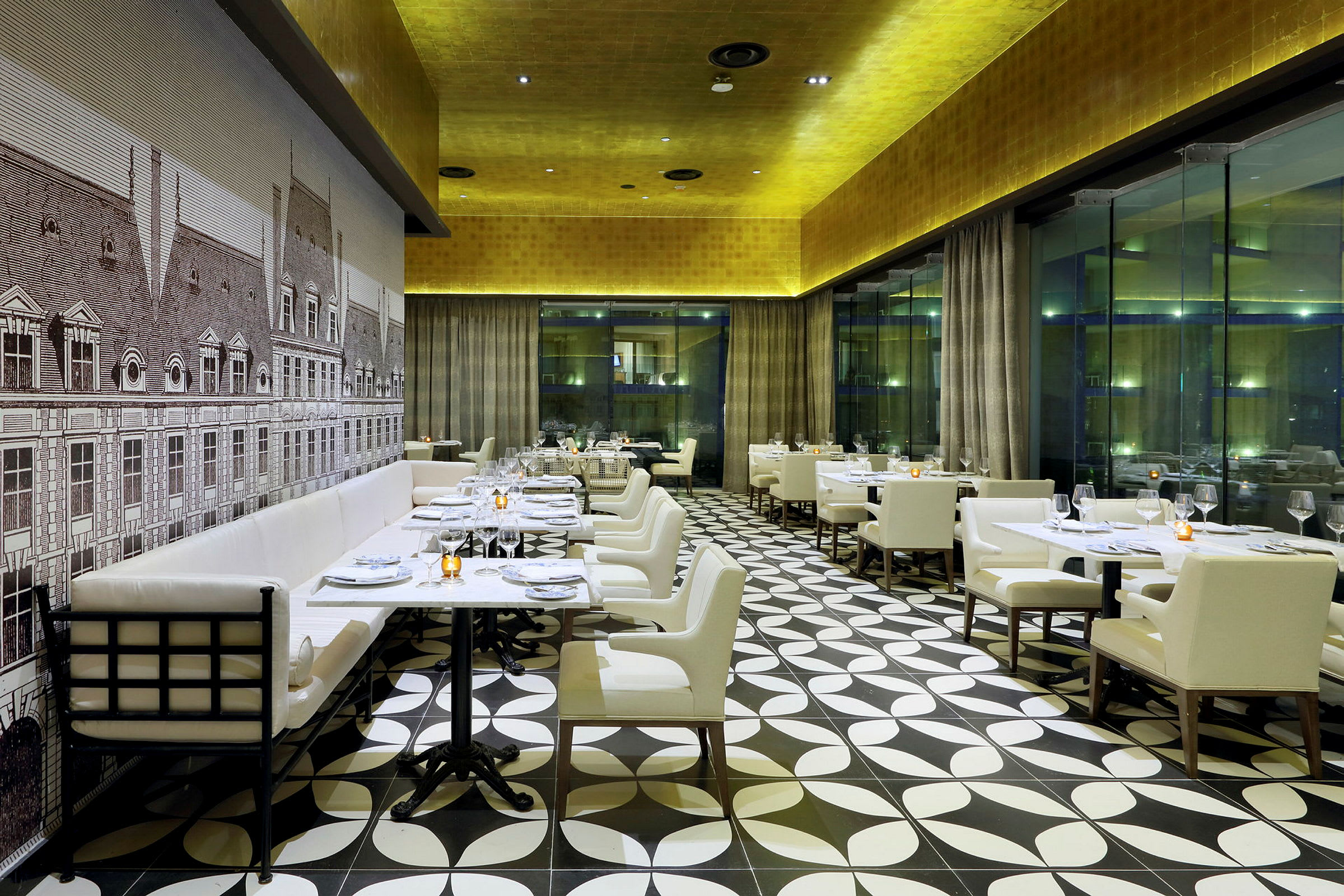 Restaurang med vita stolar, dukade bord och en dekorativ vägg med en tecknad fasad. (AI-genererad text)