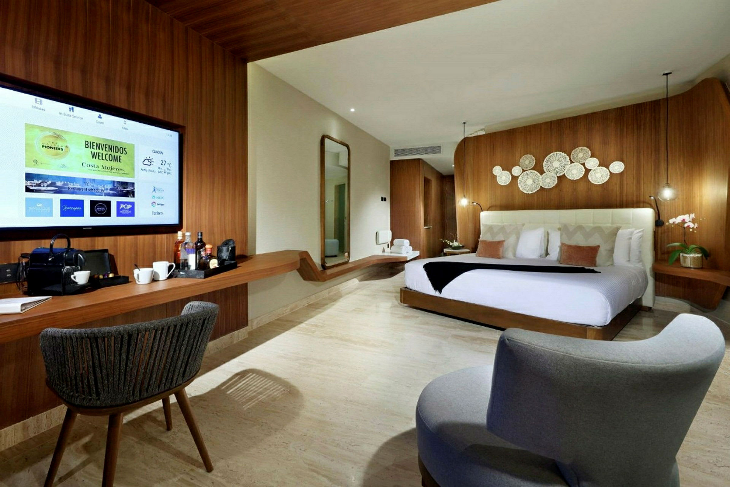Ett modernt hotellrum med en bekväm säng, dekorativa detaljer på väggen, en stor TV och en sittplats. (AI-genererad text)