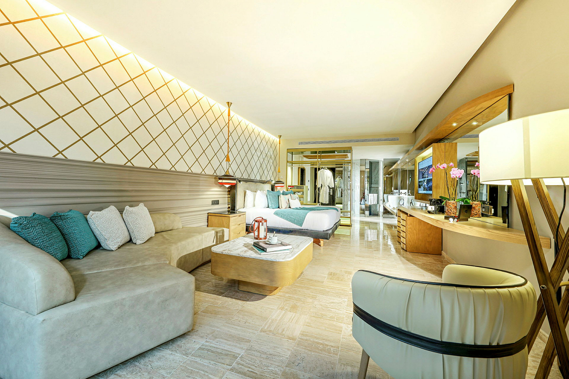 Ett stilfullt hotellrum med en säng, soffa, och modern inredning. Rummet har ett stort spegelområde och varm belysning. (AI-genererad text)