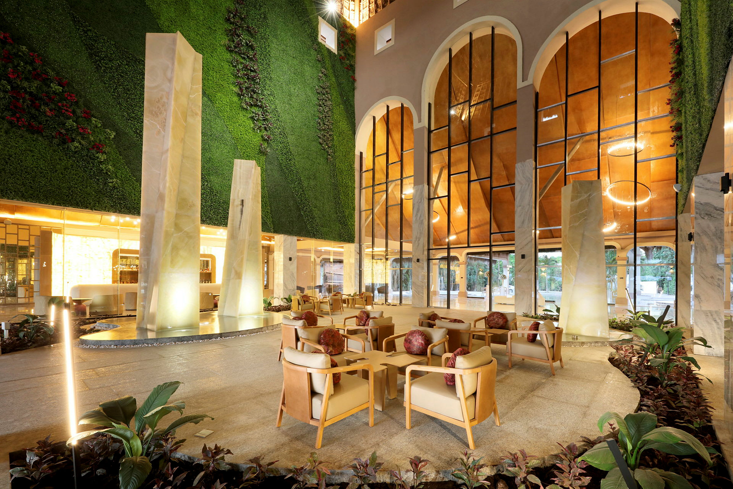 Hotellobby med modern inredning, bekväma sittplatser och grönskande väggar. (AI-genererad text)