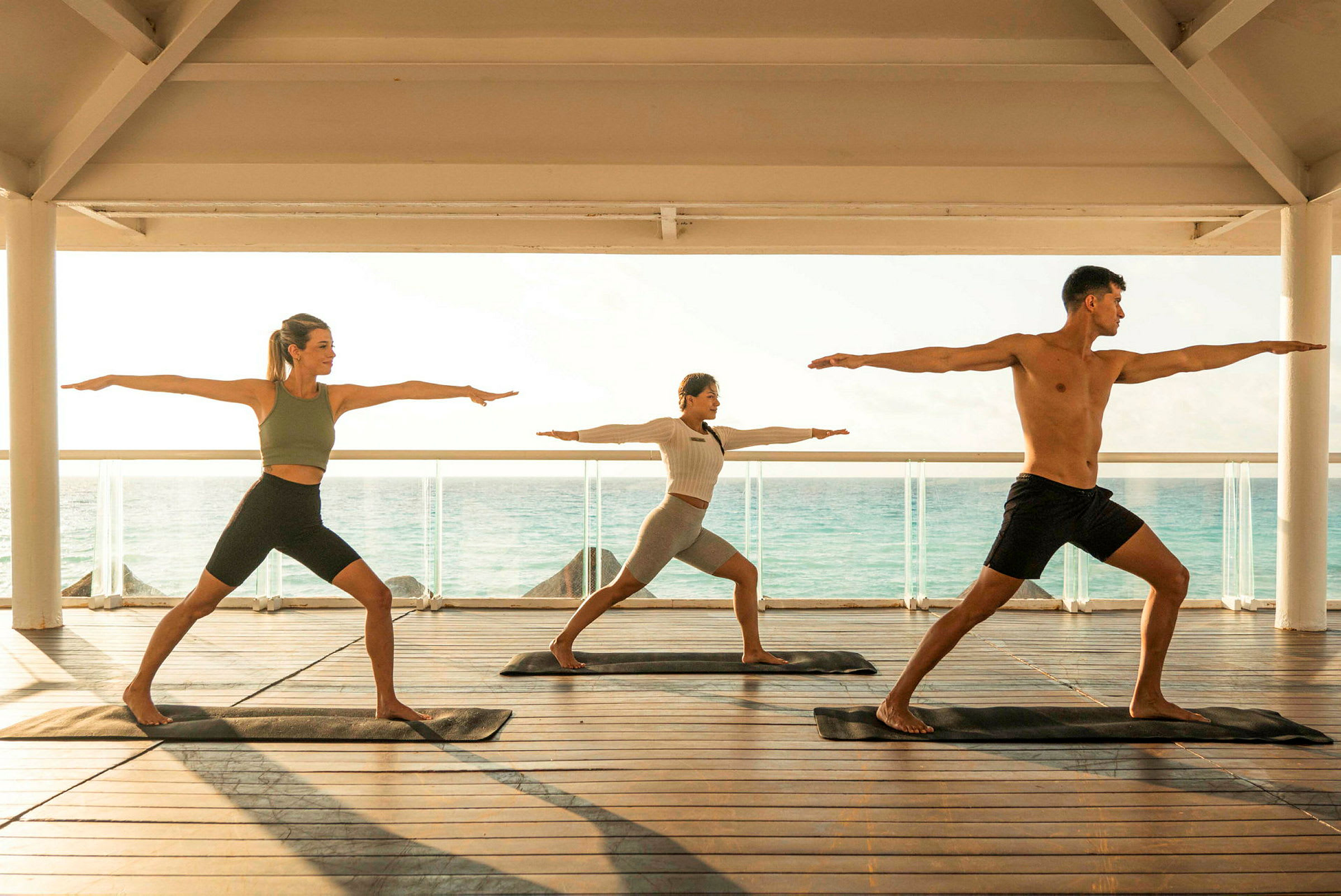 Personer tränar yoga på en terrass med havet i bakgrunden. (AI-genererad text)