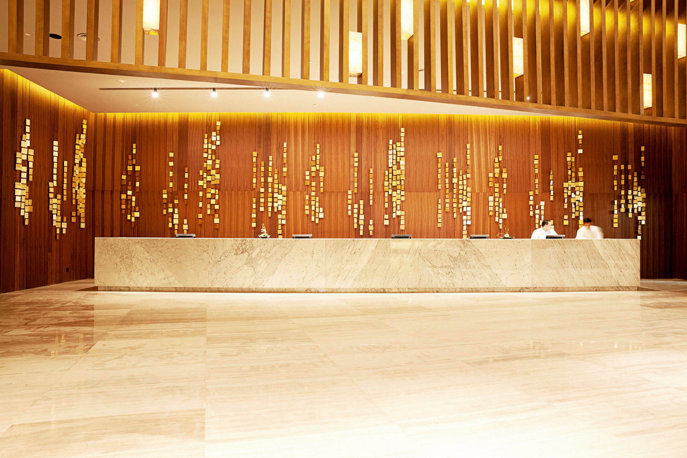 Hotellobby med receptionsdisk i ljus sten och dekorativ träpanel med guldaktiga detaljer. (AI-genererad text)