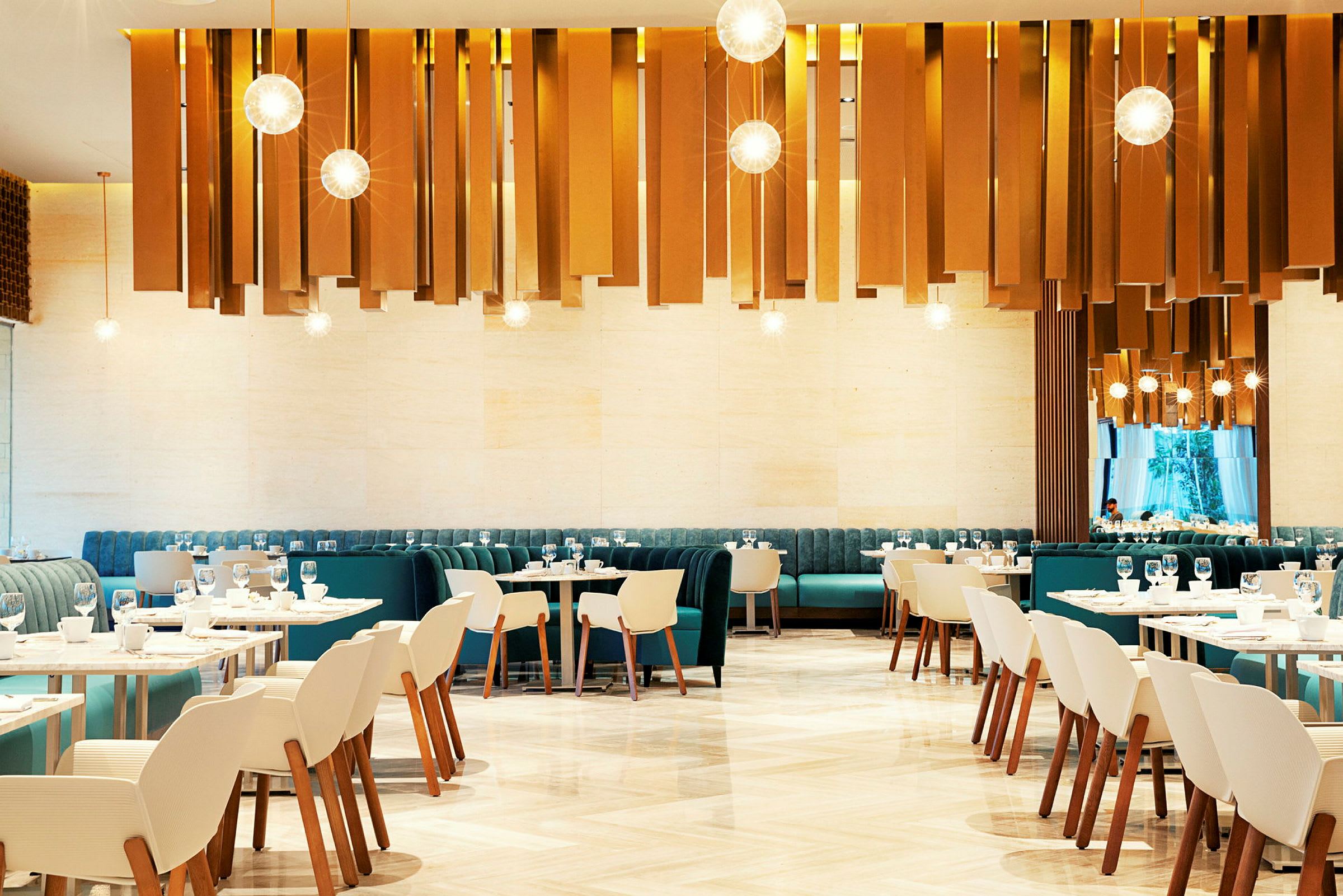 En modern restaurang med eleganta stolar och bord. Dekorativa ljuskällor hänger från taket. (AI-genererad text)