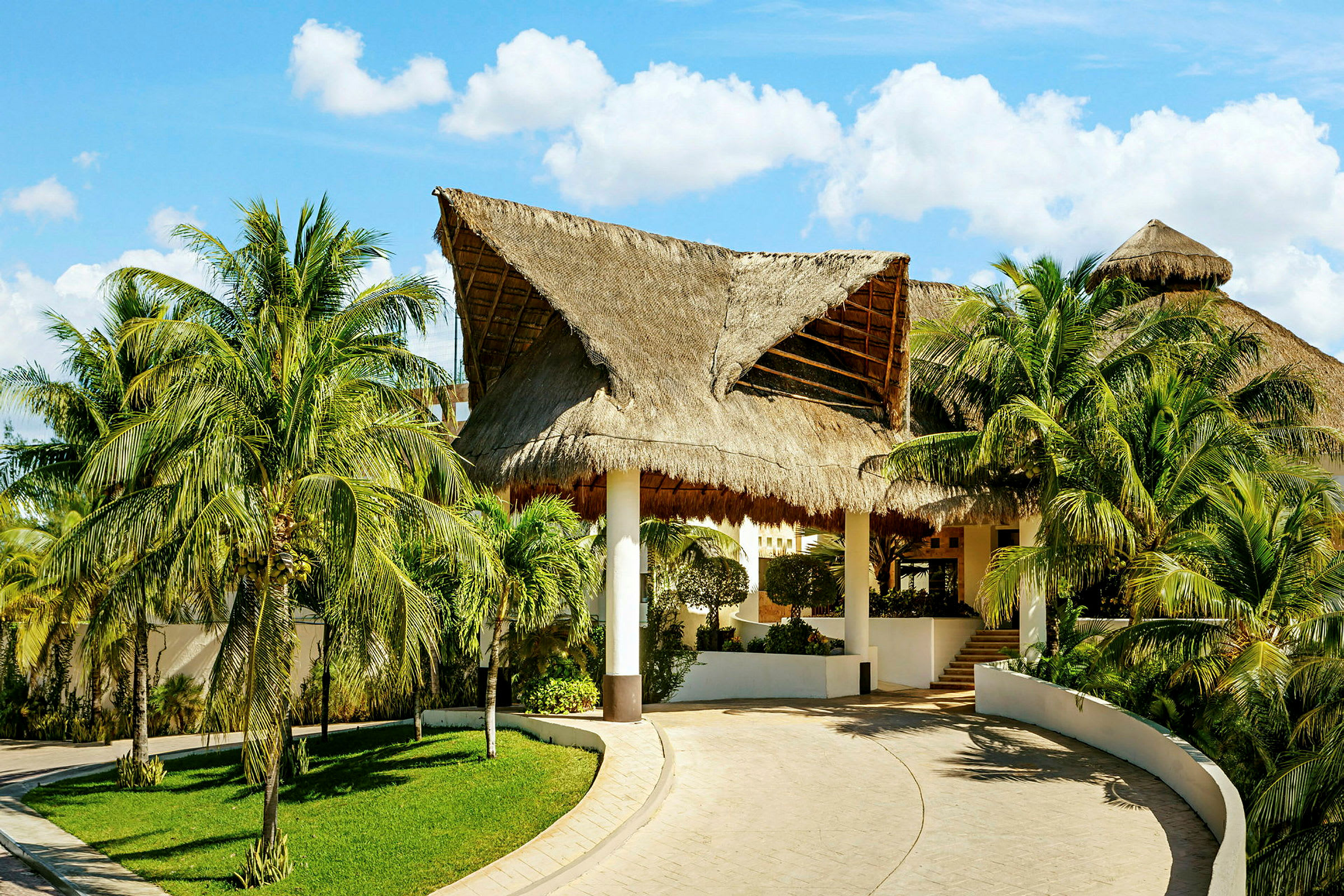 Bild av en byggnad med halmtak omgiven av palmer och grönska. (AI-genererad text)