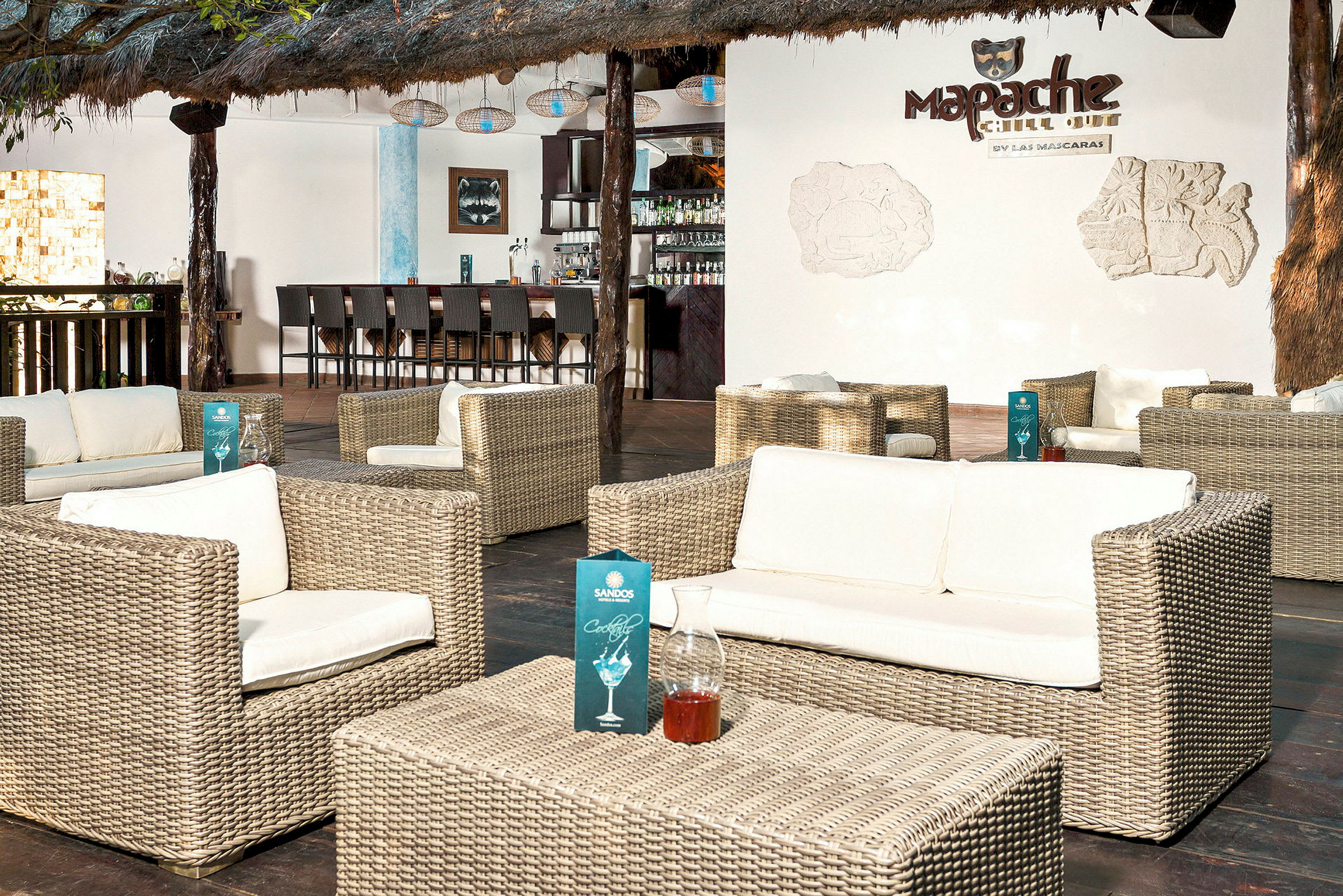 Loungeområde med flätade möbler och en bar i bakgrunden. (AI-genererad text)