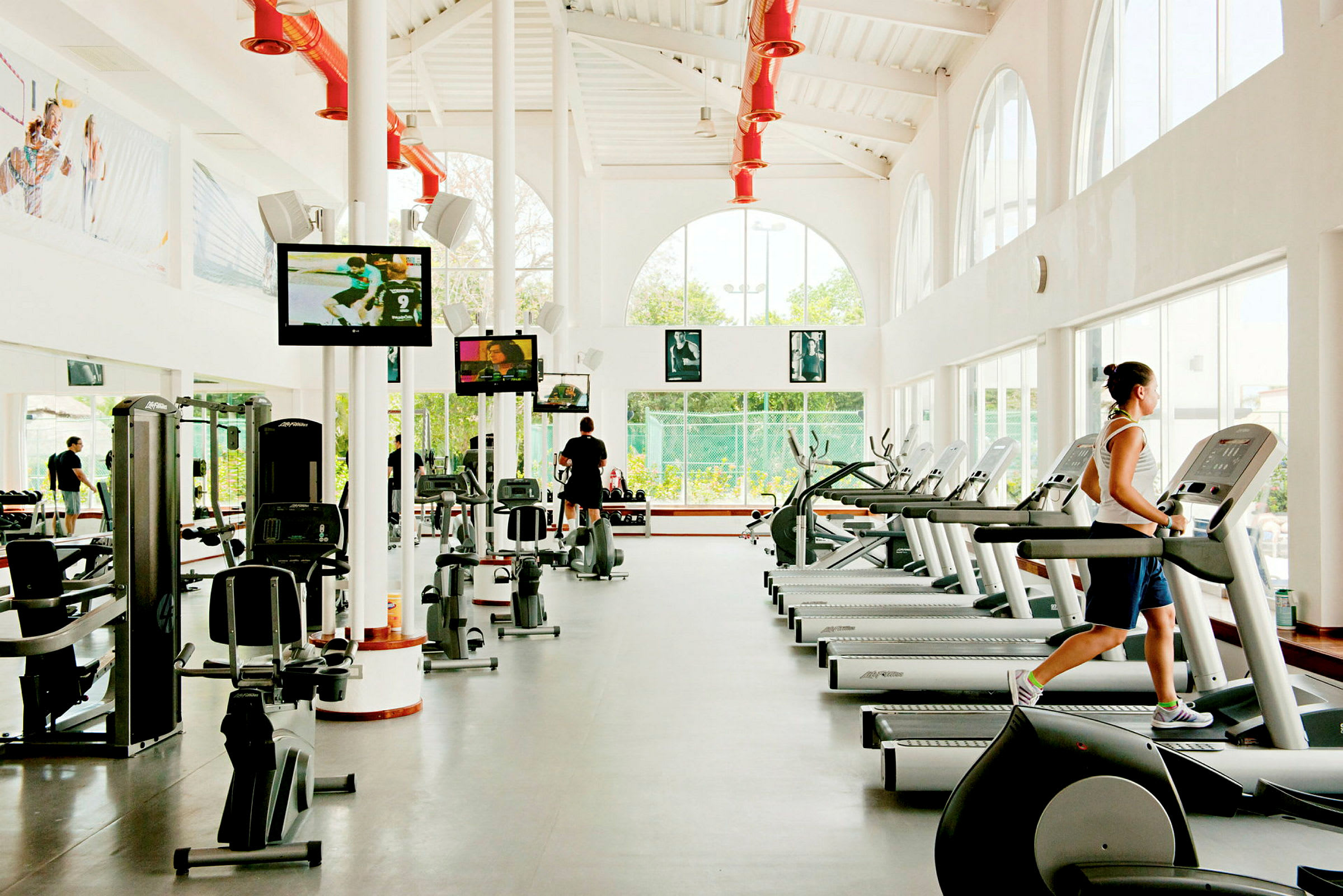 Ett modernt gym med träningsmaskiner, löpband och tv-skärmar. (AI-genererad text)