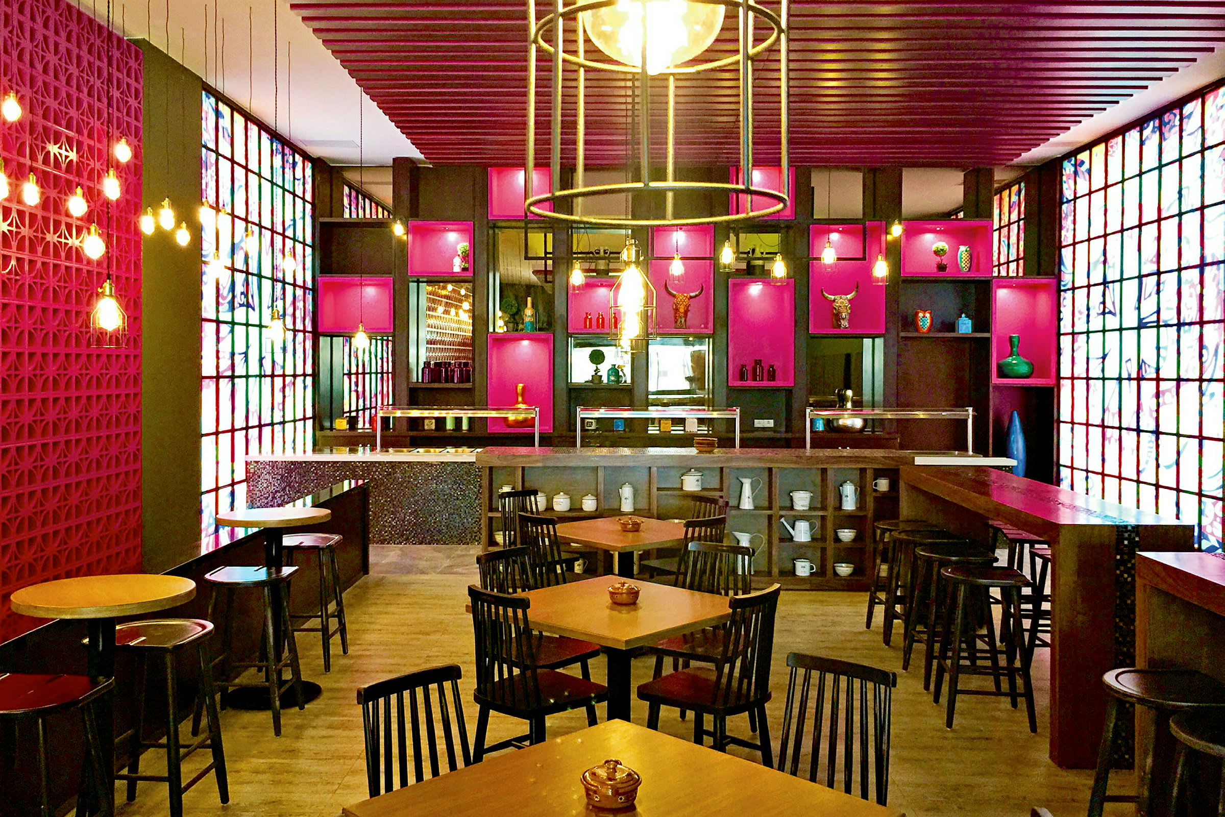 En restaurang med färgglada dekorationer, bord och stolar uppställda, en bar och hyllor fyllda med prydnader. (AI-genererad text)