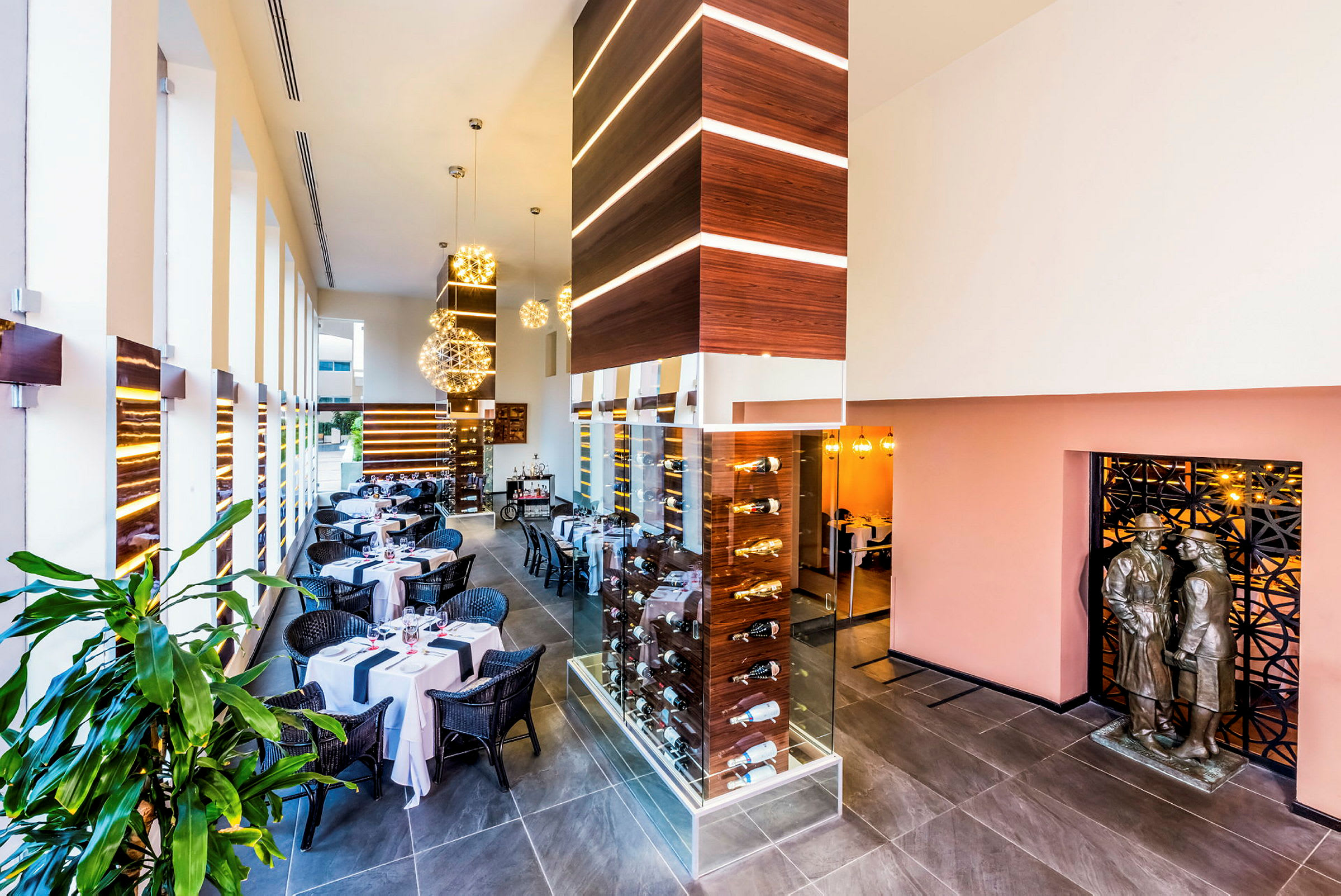 Interiör av en modern restaurang med dukade bord, eleganta dekorationer och en glasskåp med flaskor. (AI-genererad text)