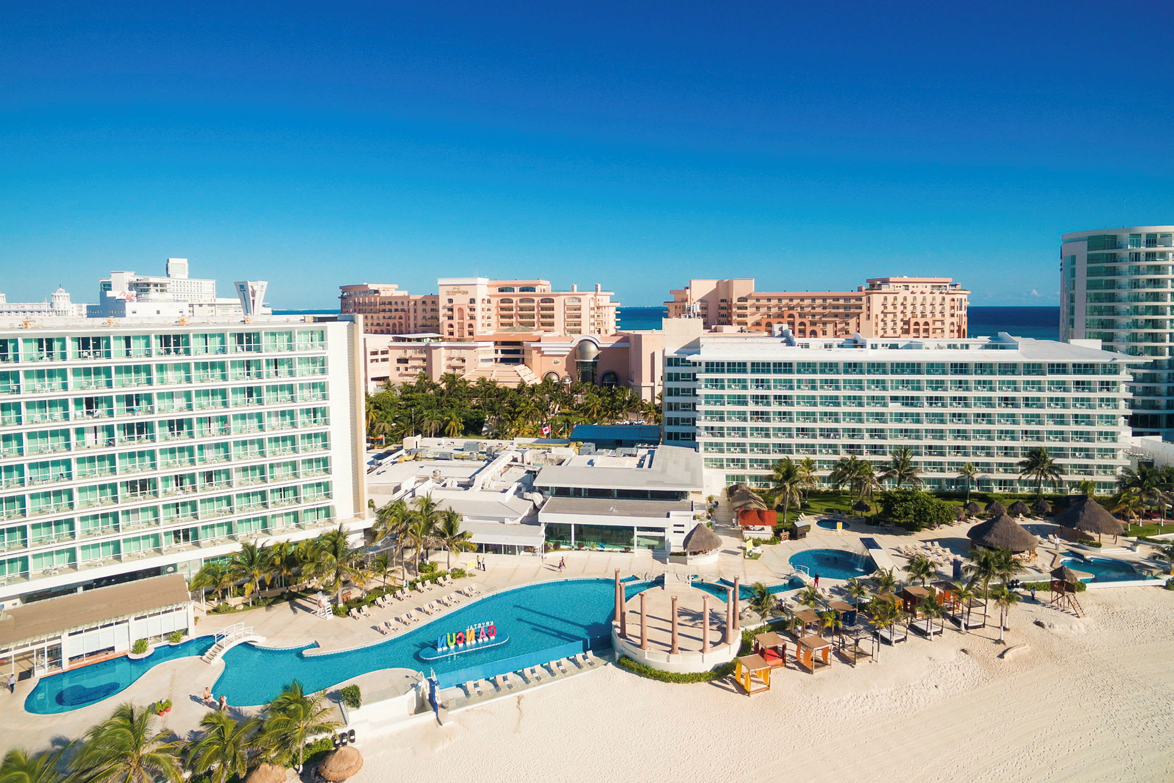 En strandnära resort med stora hotellbyggnader omgivna av pooler och palmer. (AI-genererad text)