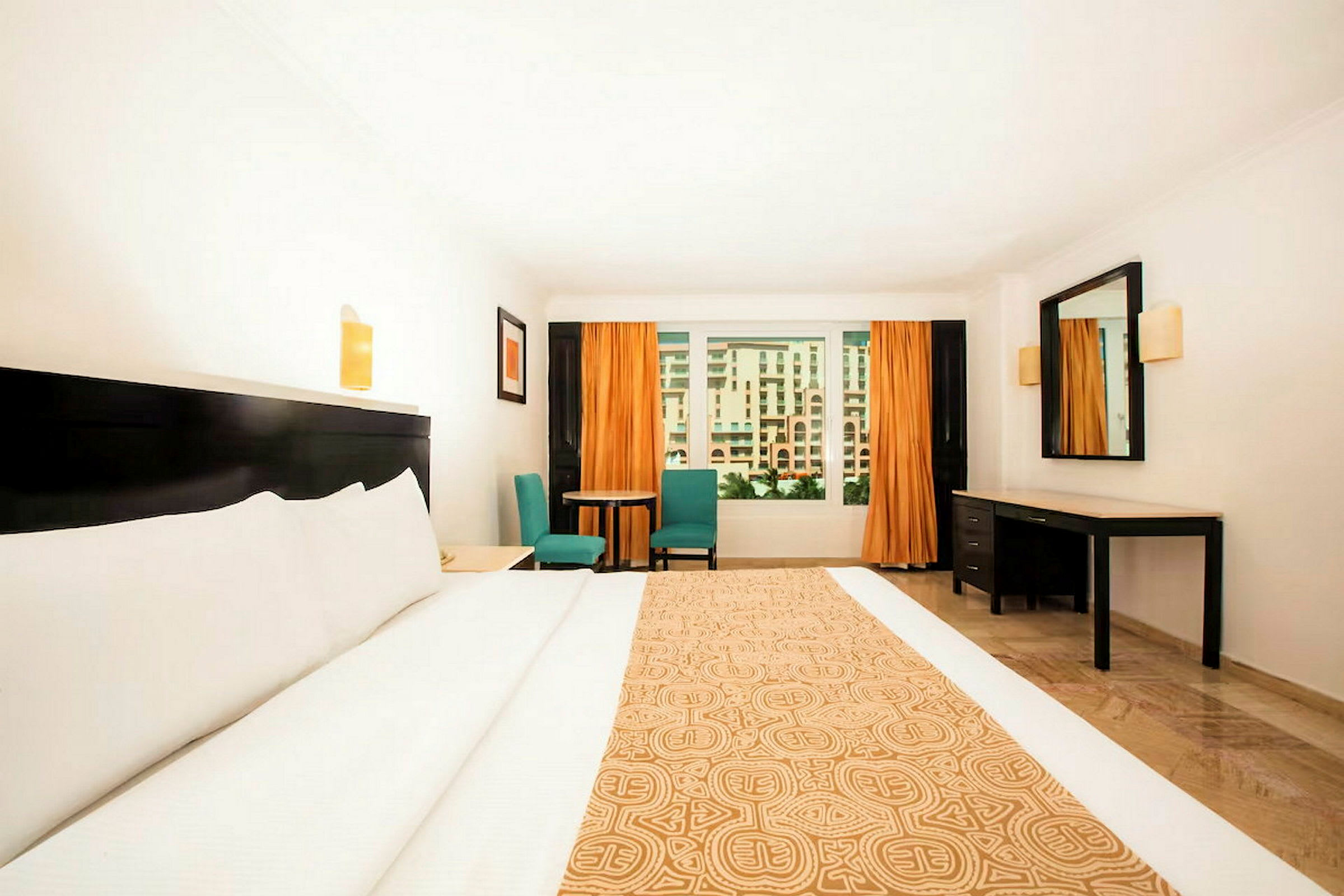 Ett hotellrum med en stor säng, ett skrivbord, en sittgrupp samt ett fönster med utsikt. (AI-genererad text)
