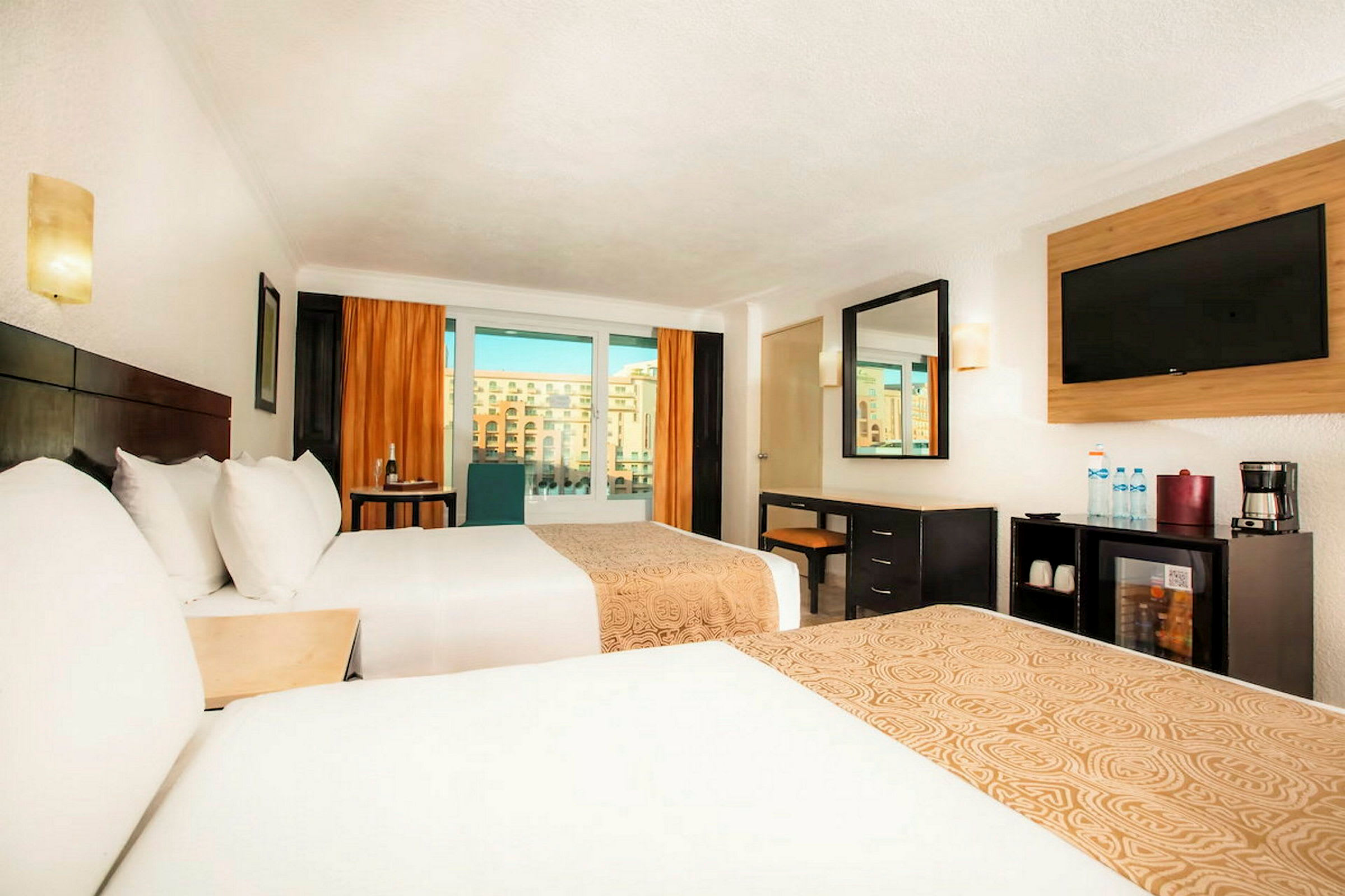 Hotellrum med två sängar, ett skrivbord, en tv och stora fönster med utsikt. (AI-genererad text)
