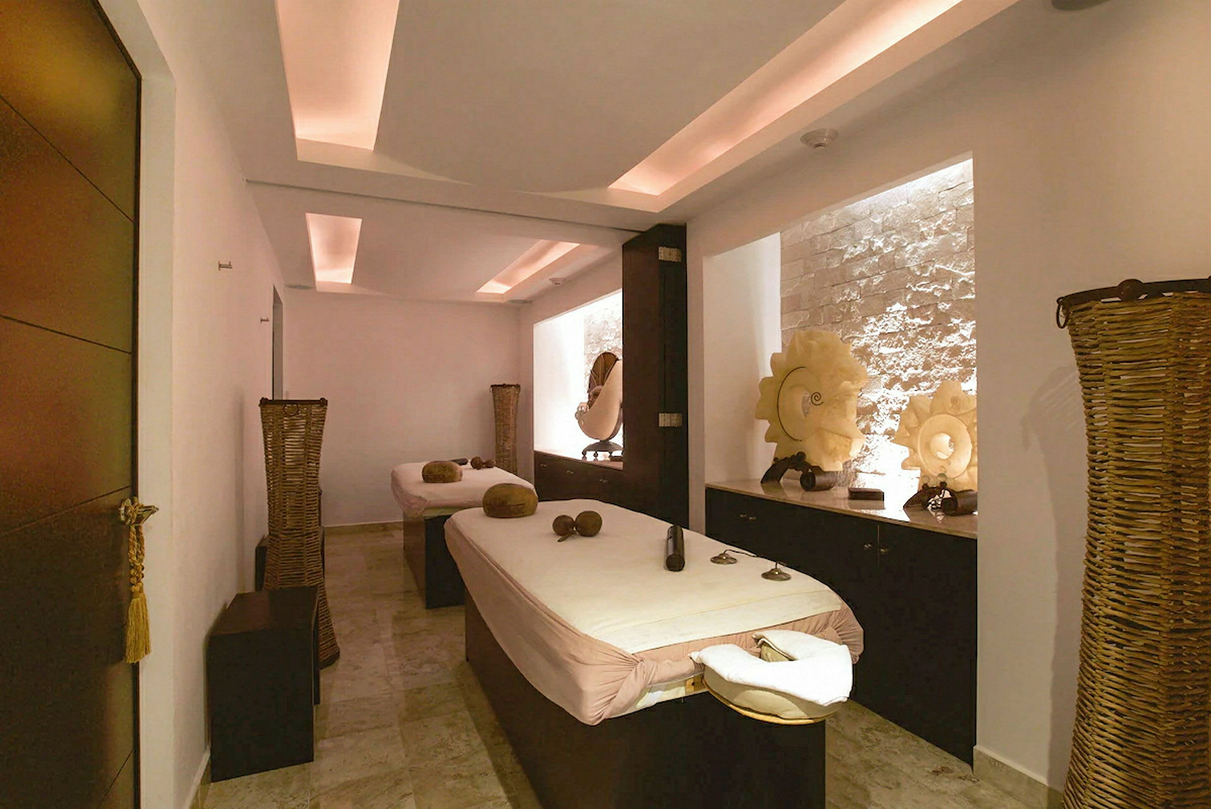 Ett spa-rum med två massagebänkar och avslappnande dekorationer. (AI-genererad text)
