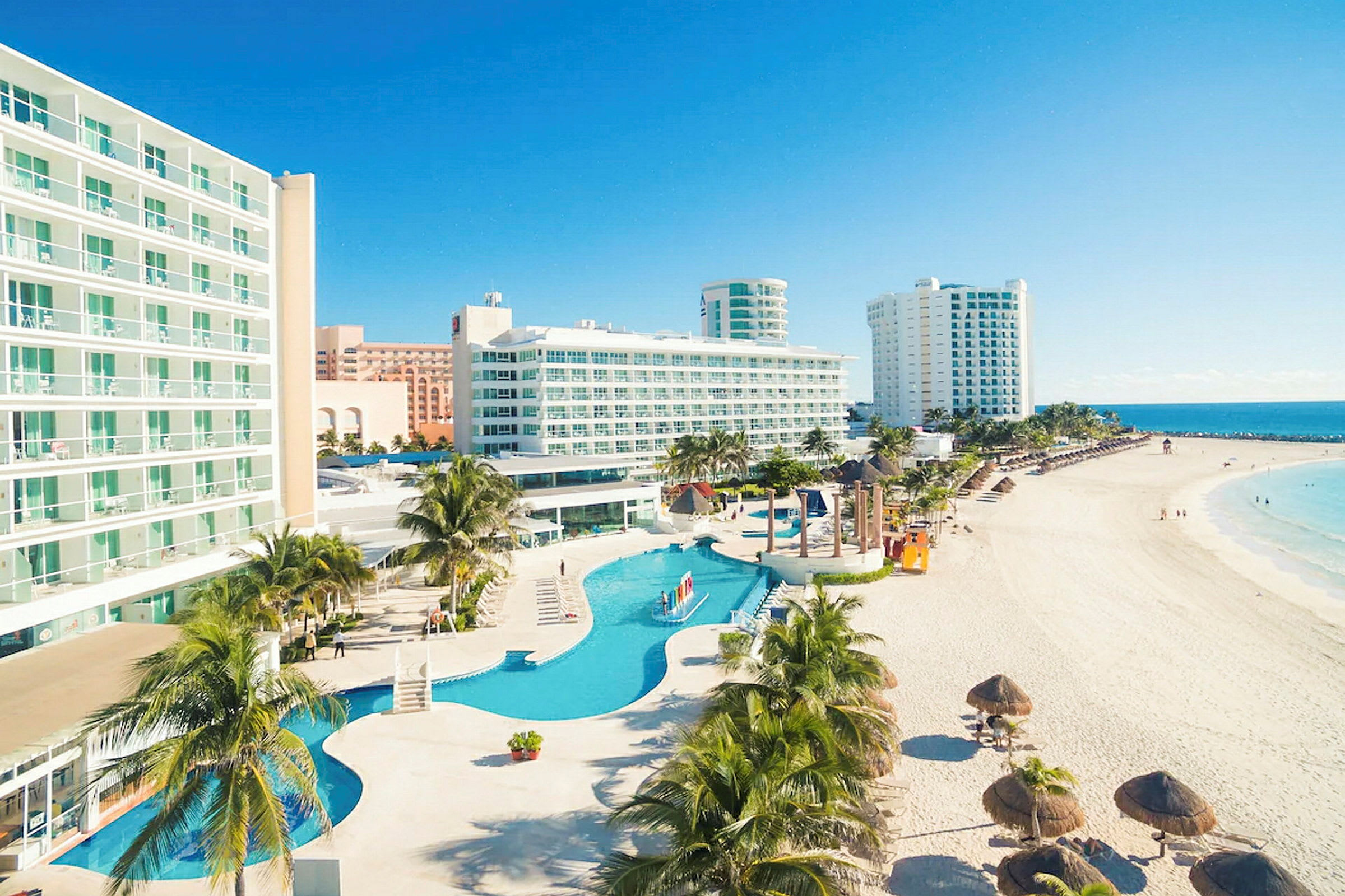 Bild av hotell vid stranden med pool och palmer. (AI-genererad text)
