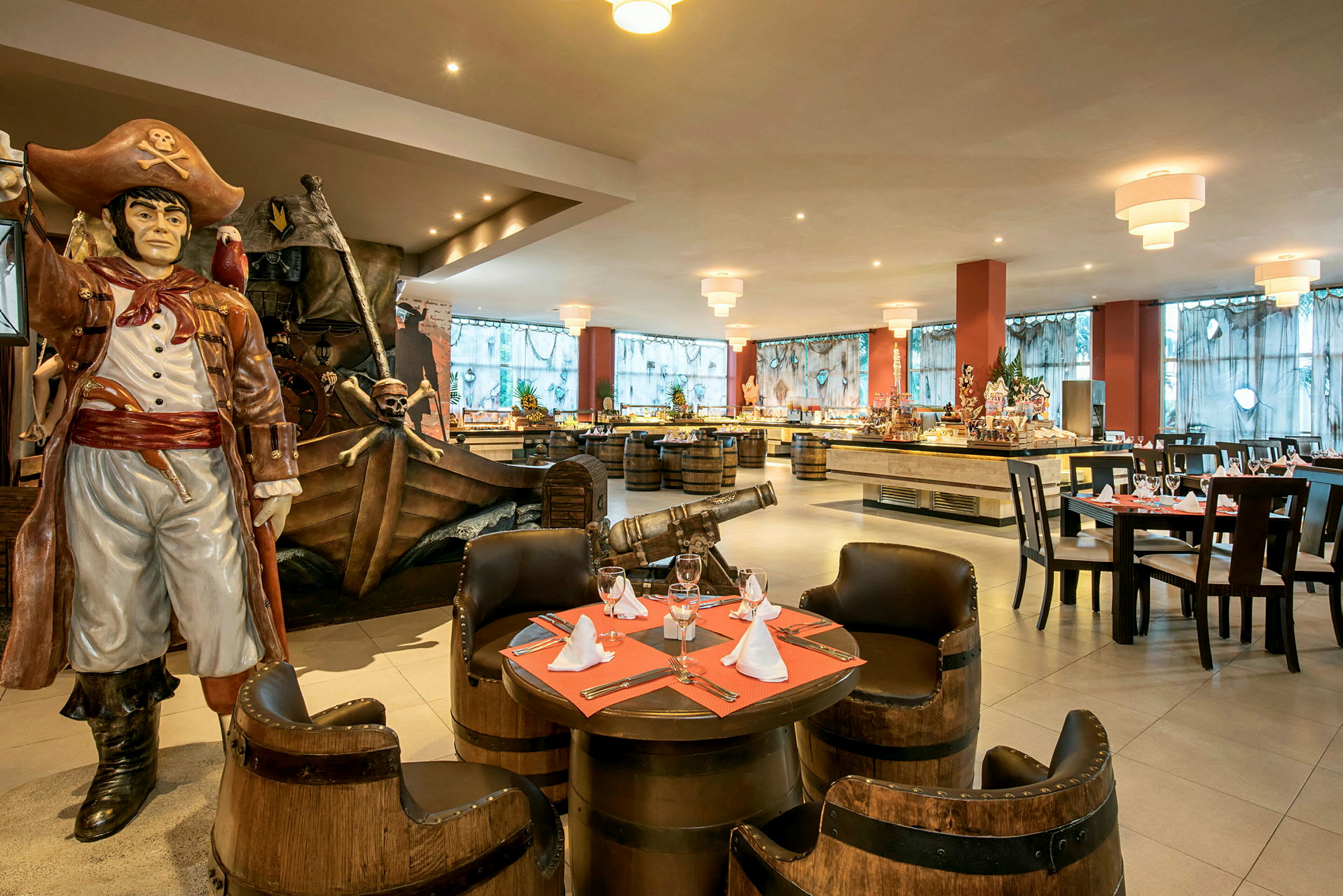 Bild på en restaurang med pirattema, där det finns en stor staty av en pirat bredvid dekorationer som en kanon och ett skepp. Restaurangen är inredd med bord och stolar. (AI-genererad text)