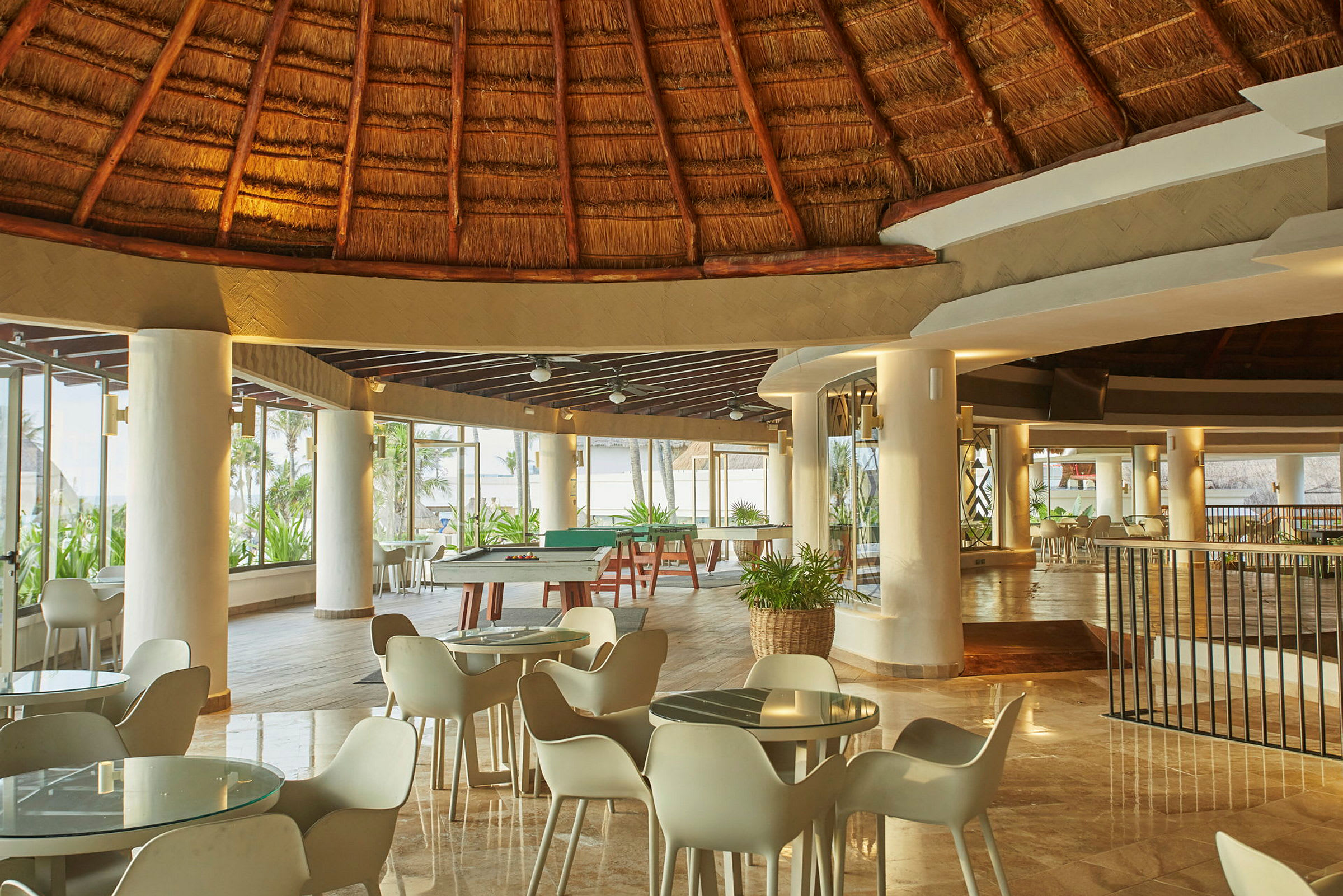 Interiör av en strandnära restaurang med ett halmtak och ljusa utemöbler. (AI-genererad text)