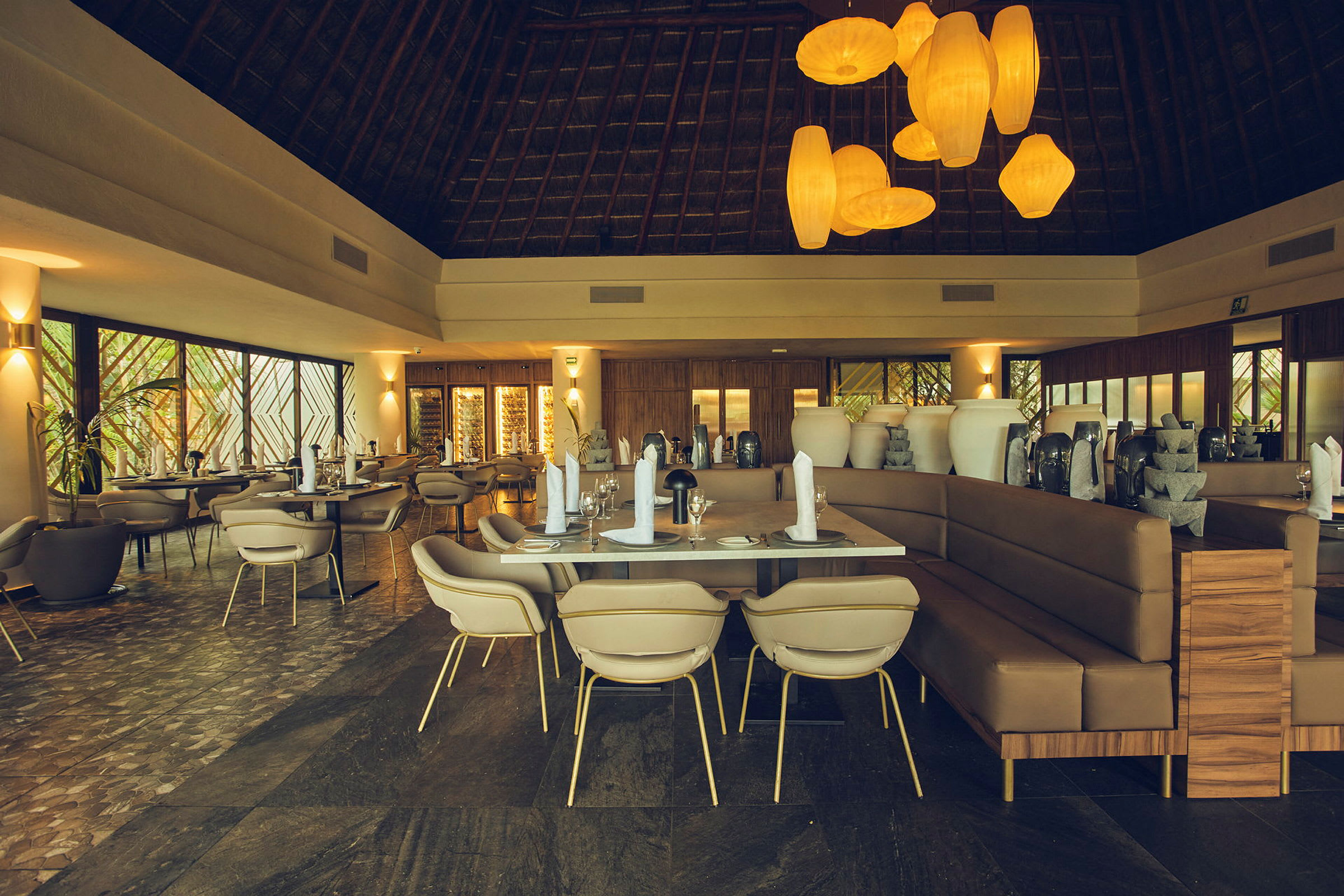 Bild av en elegant restaurang med dukade bord, moderna stolar och stora dekorativa vaser. Taket är högt med synliga trästrukturer och rummet har varm belysning. (AI-genererad text)