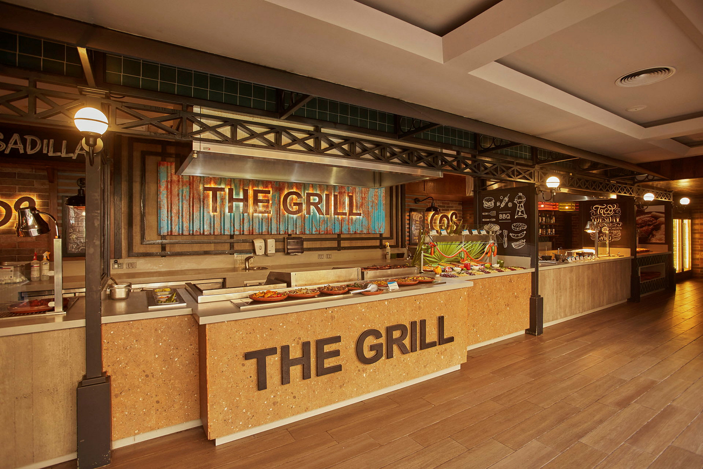 Bufféområde med en grillstation märkt 'The Grill' och matuppställningar. (AI-genererad text)