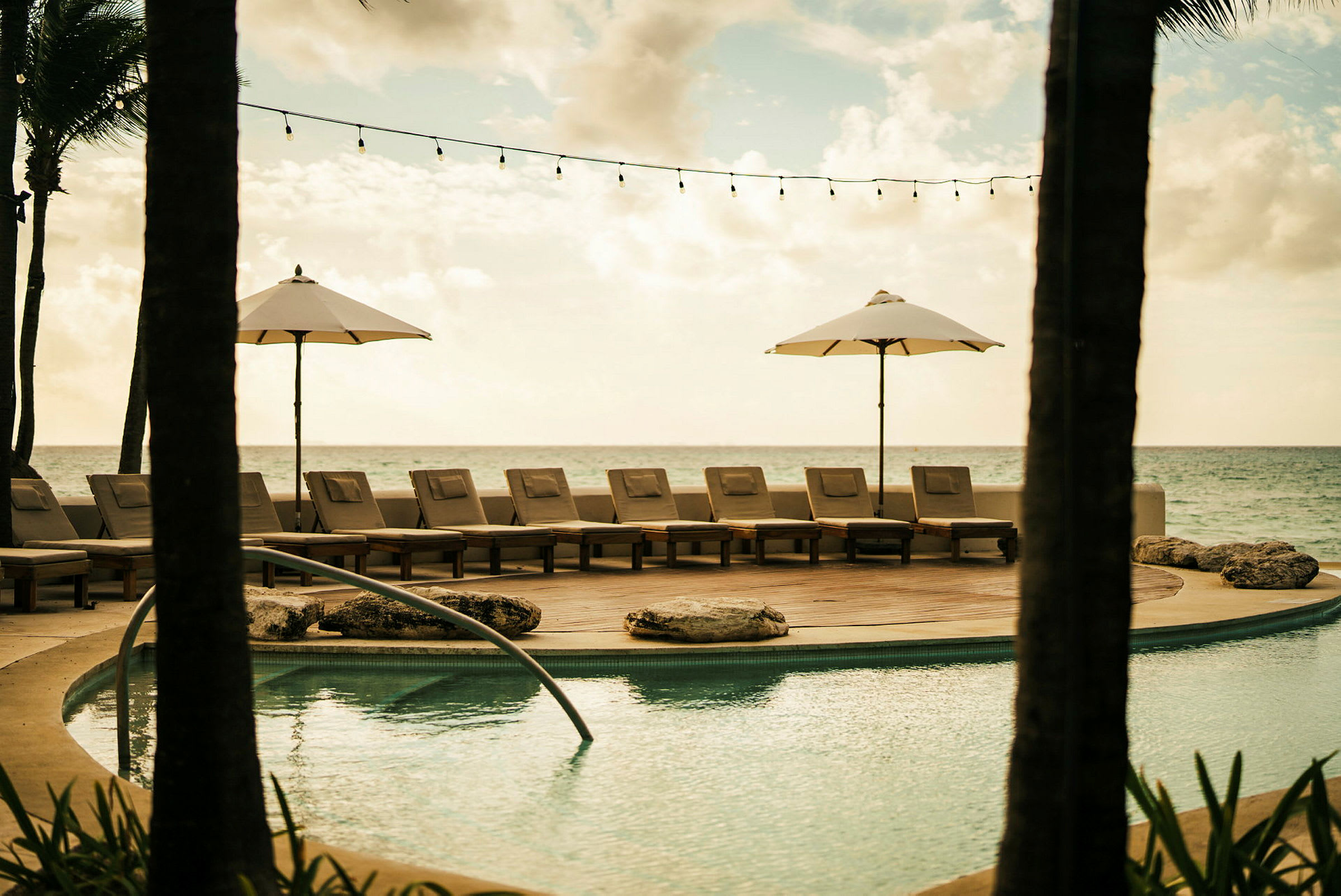 En pool vid havet med solstolar och parasoller. (AI-genererad text)