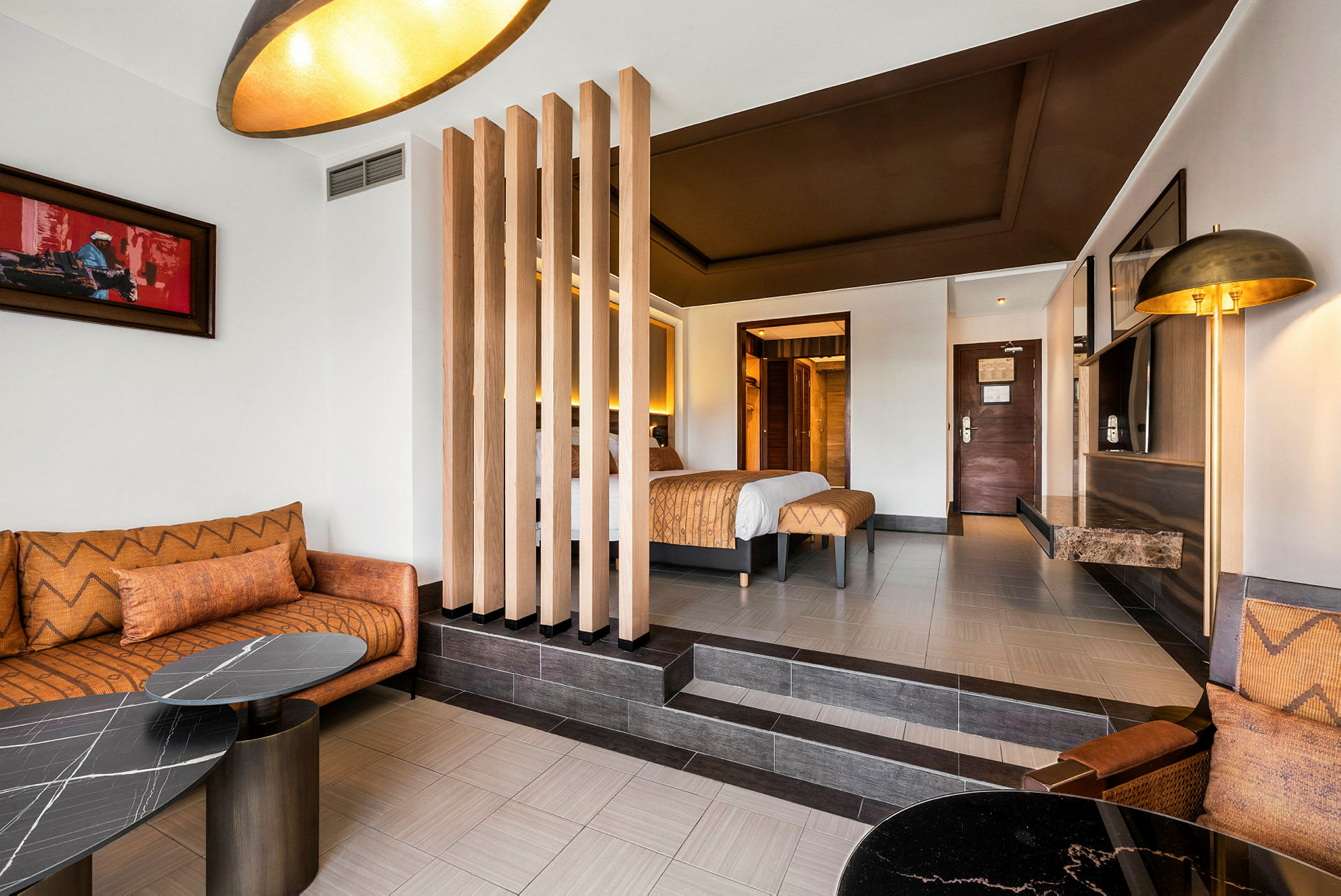 Hotellrum med säng, sittgrupp och inredning i jordnära toner. (AI-genererad text)