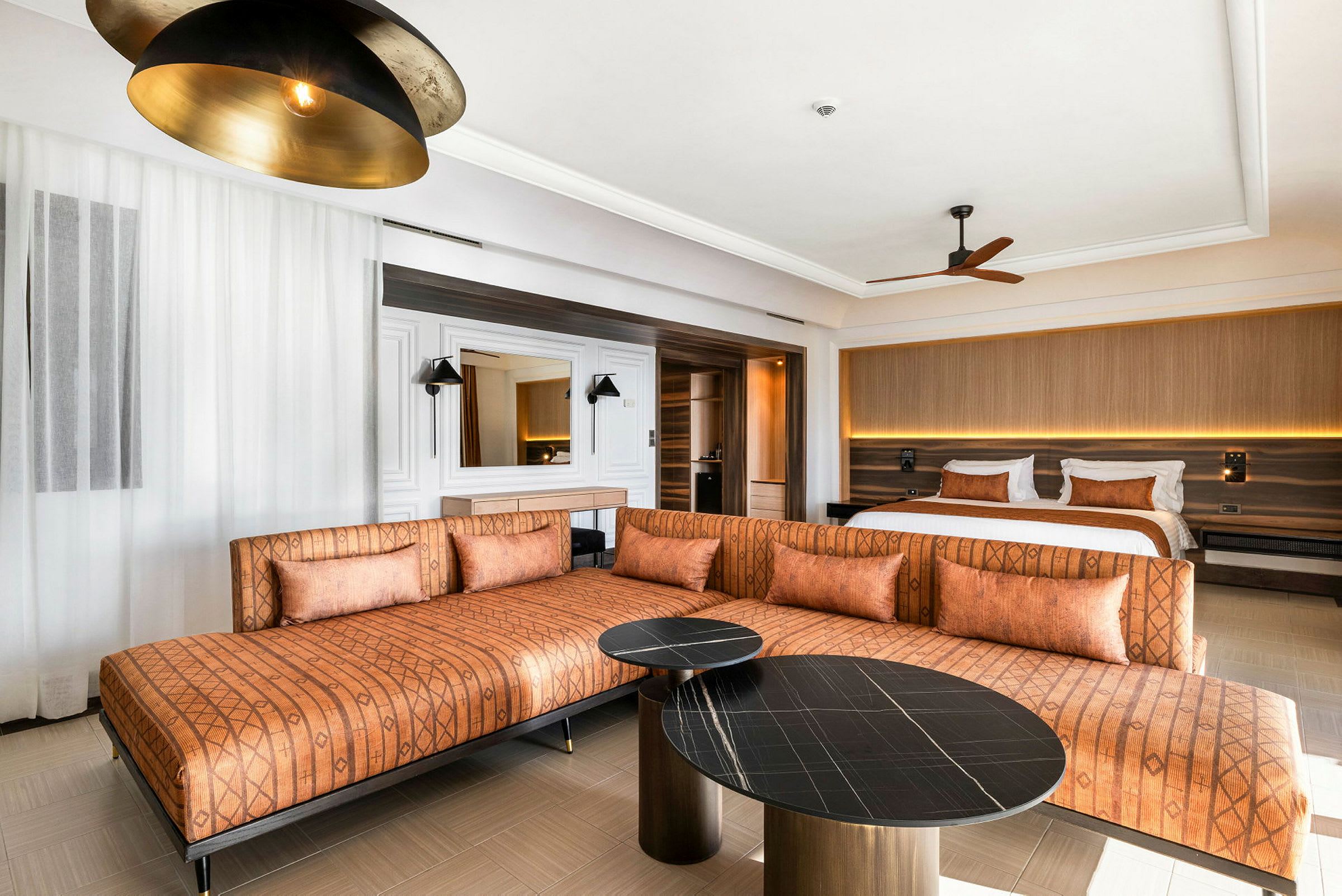 Interiör av ett hotellrum med en orange soffa, två bord och en säng. (AI-genererad text)