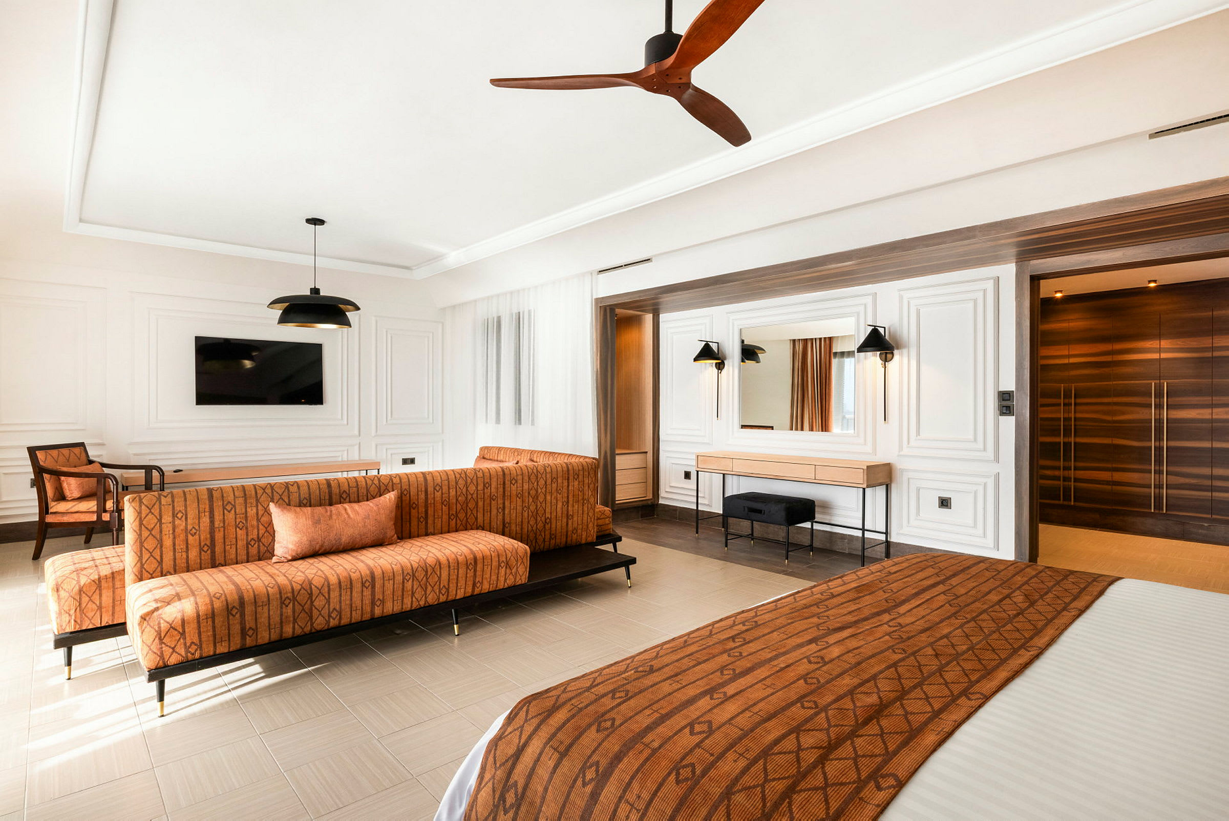 Ett hotellrum med modern inredning, inkluderande en orange soffa och ett sängöverkast i matchande färg. (AI-genererad text)