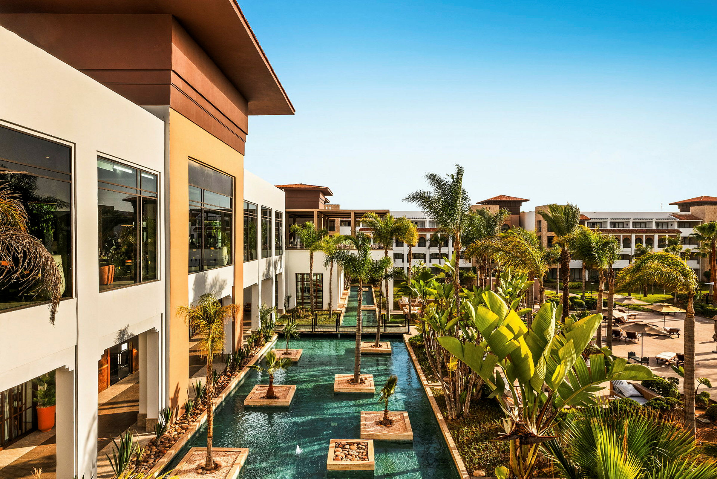 Bild av ett hotell med en pool och omgivande palmträd. (AI-genererad text)