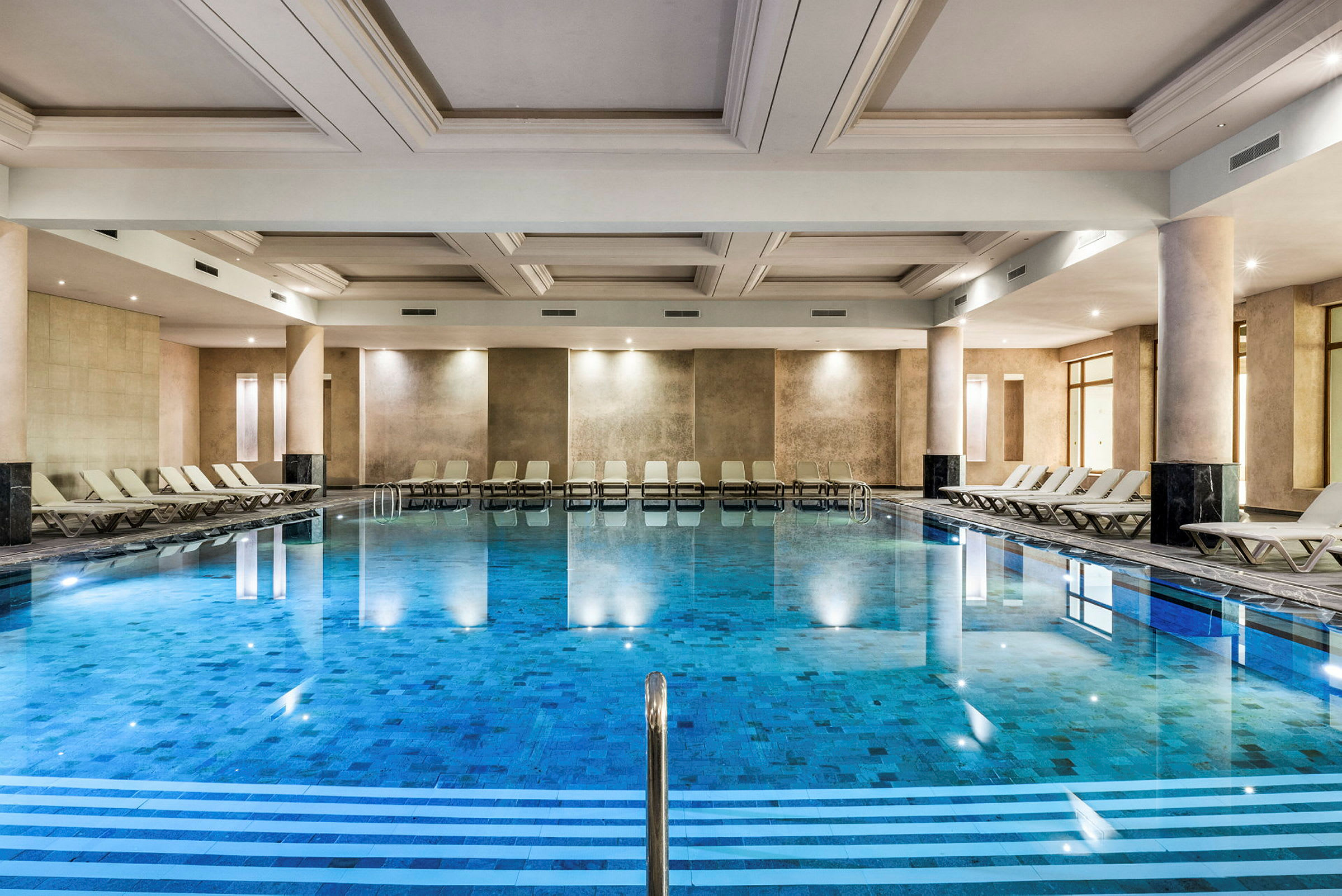 En inomhuspool med solstolar vid sidorna. (AI-genererad text)