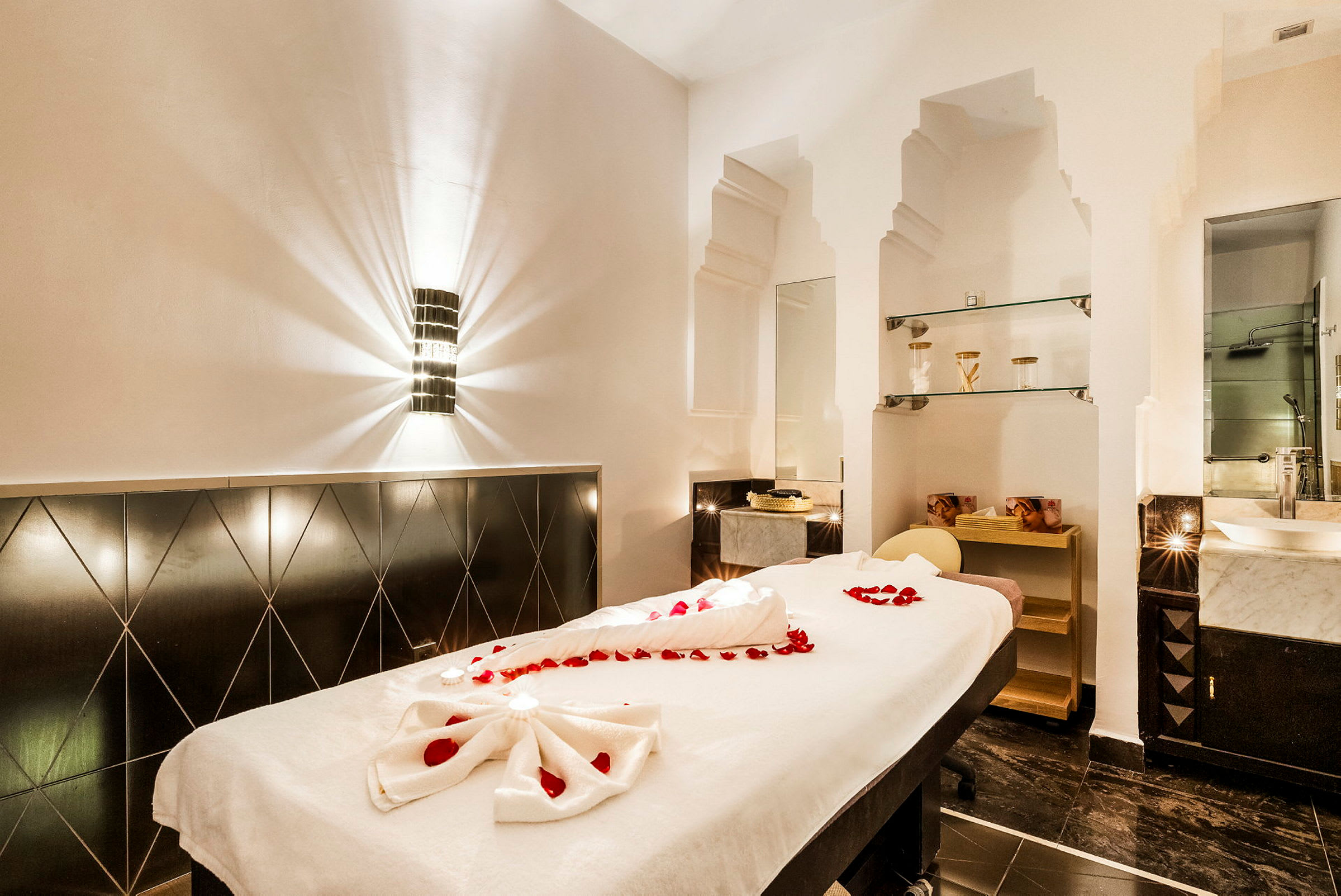 Ett spa-rum med massagebänk dekorerad med röda rosenblad. (AI-genererad text)