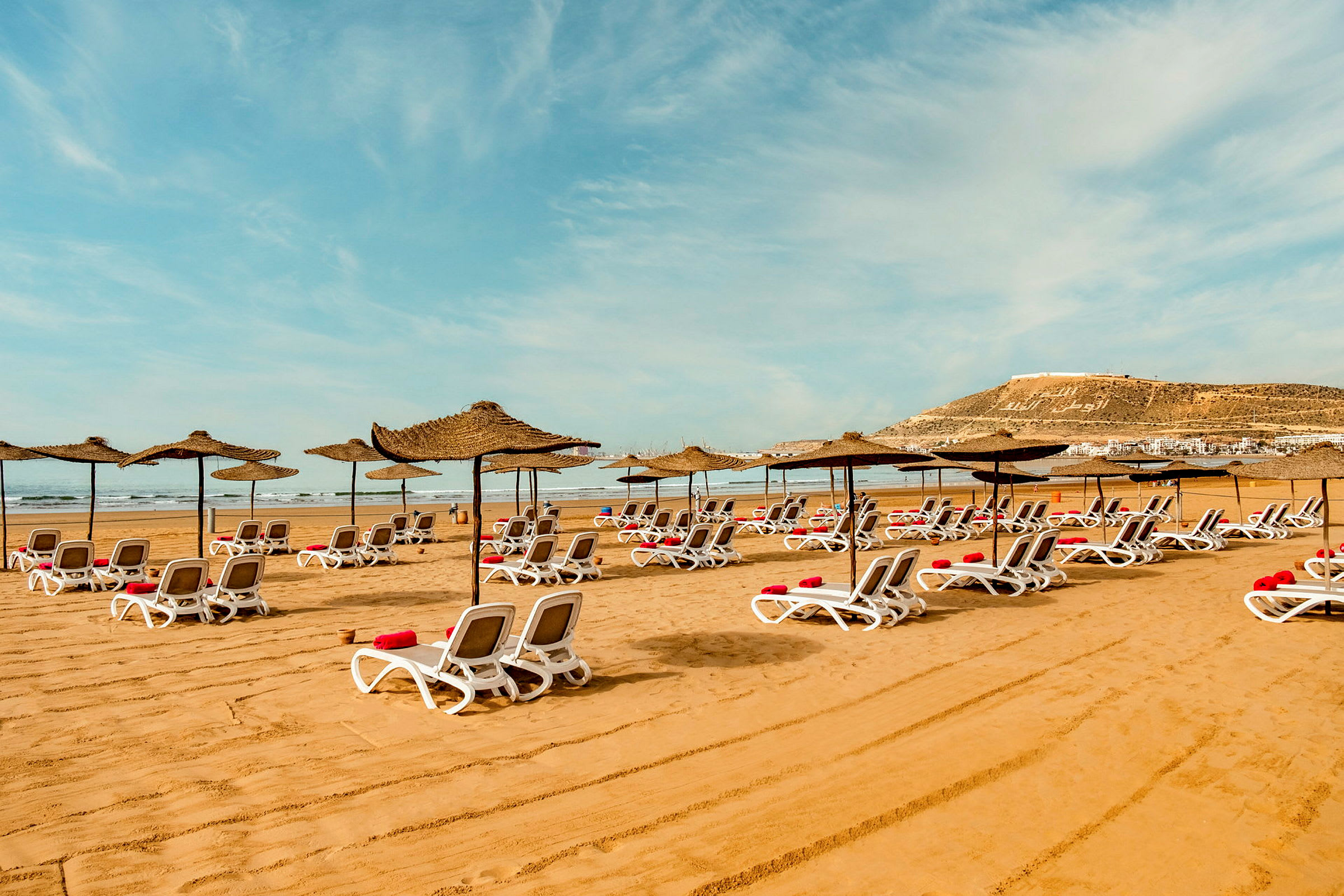Solstolar med parasoller på sandstrand. (AI-genererad text)