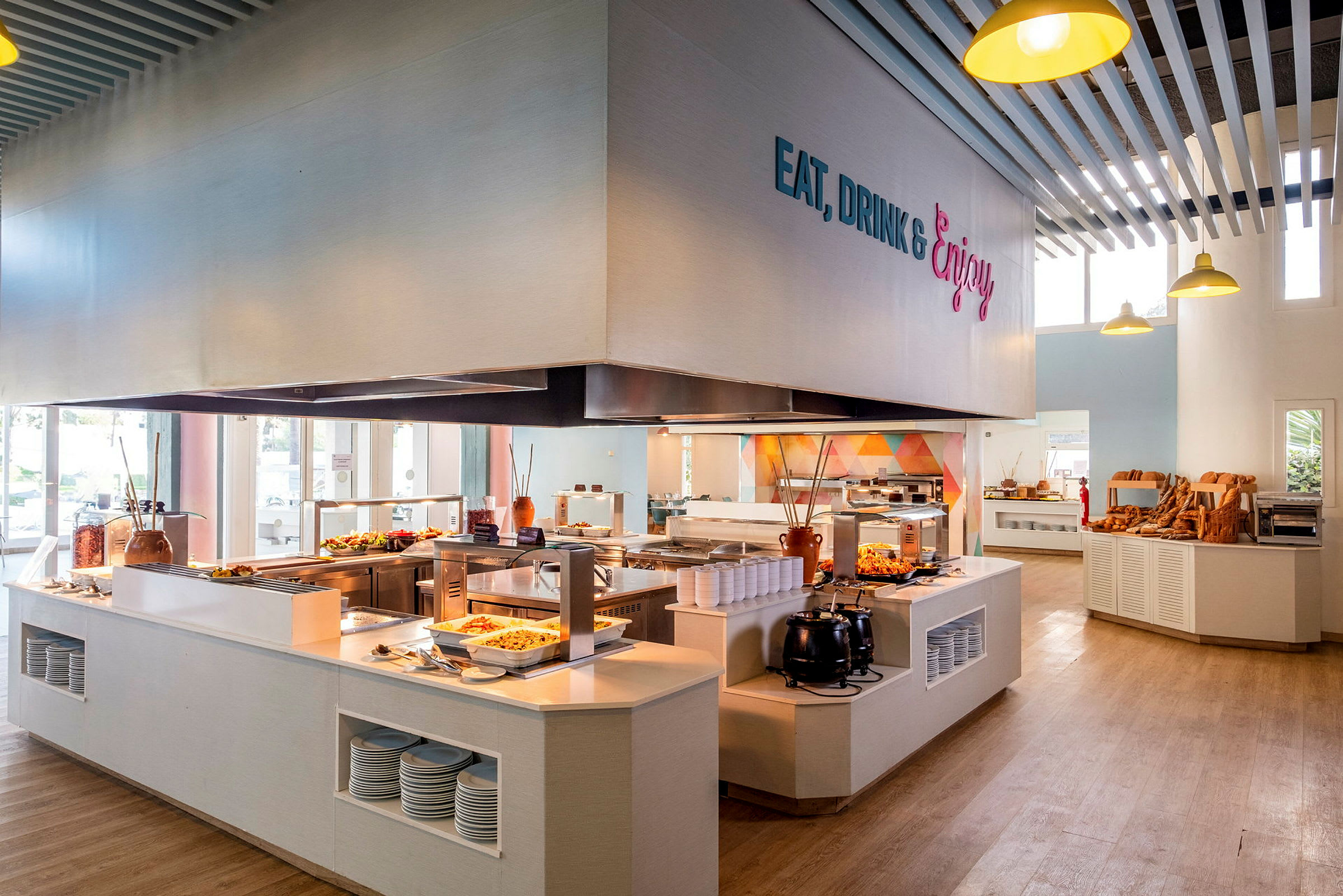 En cafeteria med självservering, där mat presenteras på diskar och brödutbud syns på hyllor. (AI-genererad text)