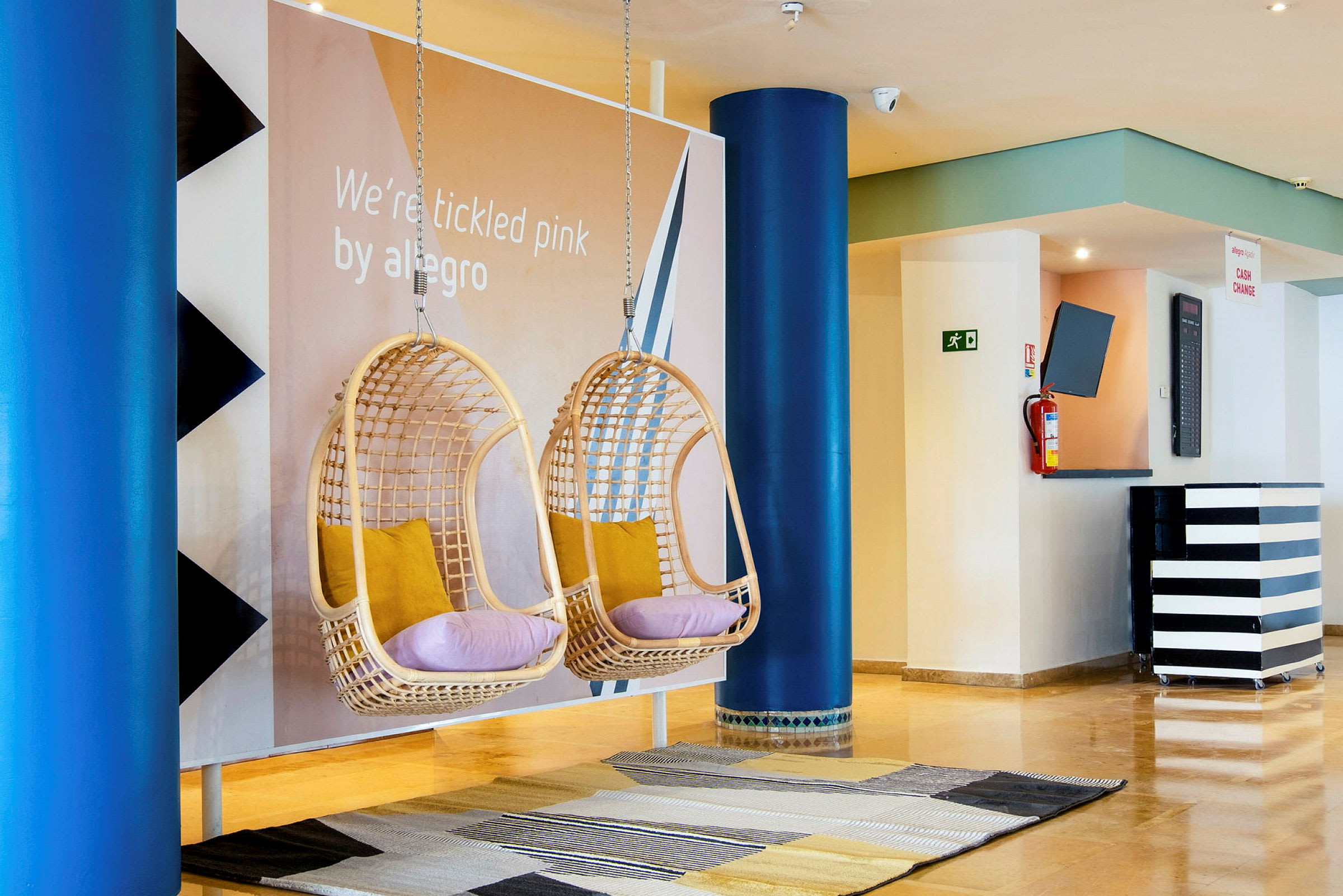 Två hängande stolar med kuddar i en hotellobby. (AI-genererad text)
