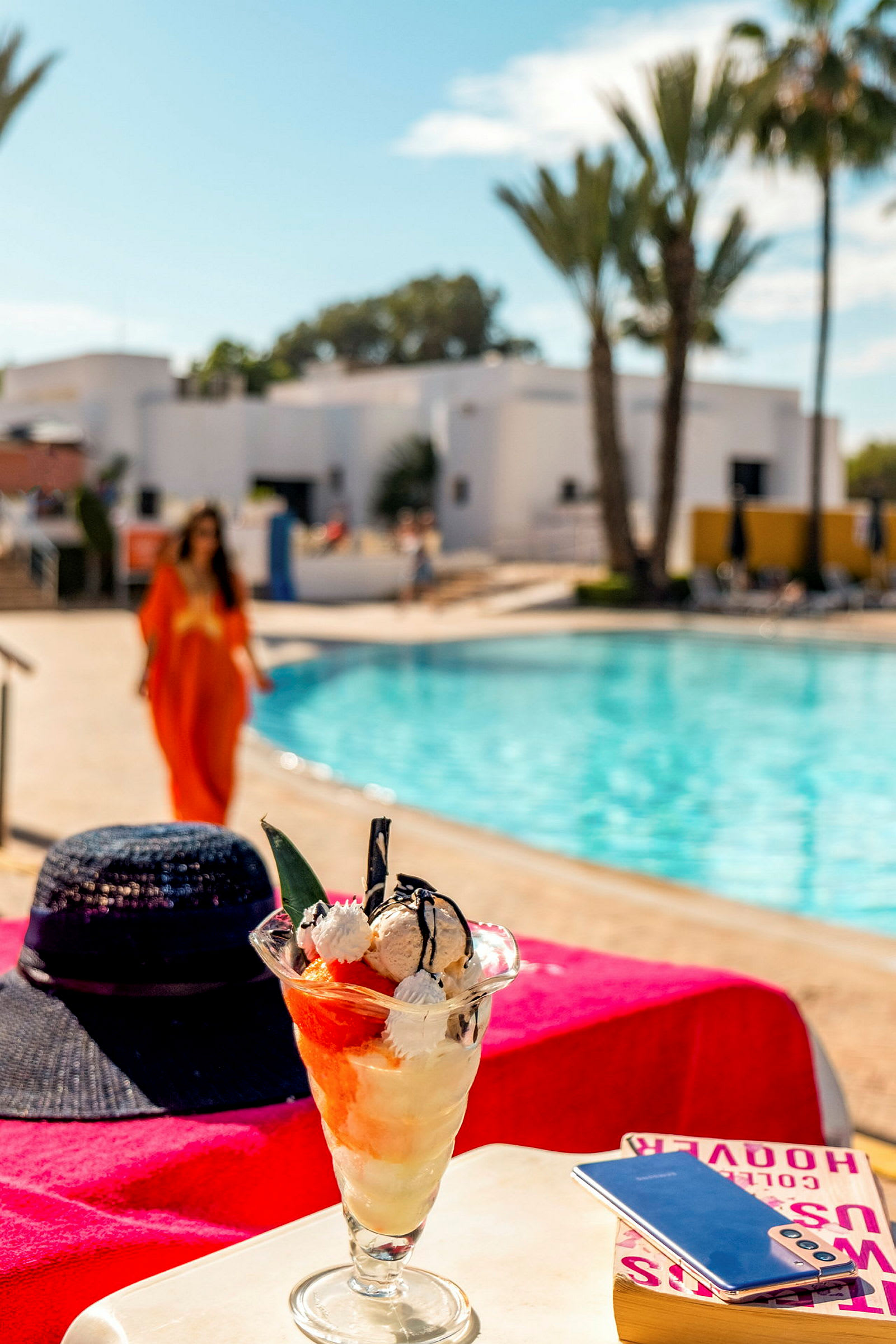 Glassdessert med frukt och vispgrädde på ett bord vid poolområde. (AI-genererad text)