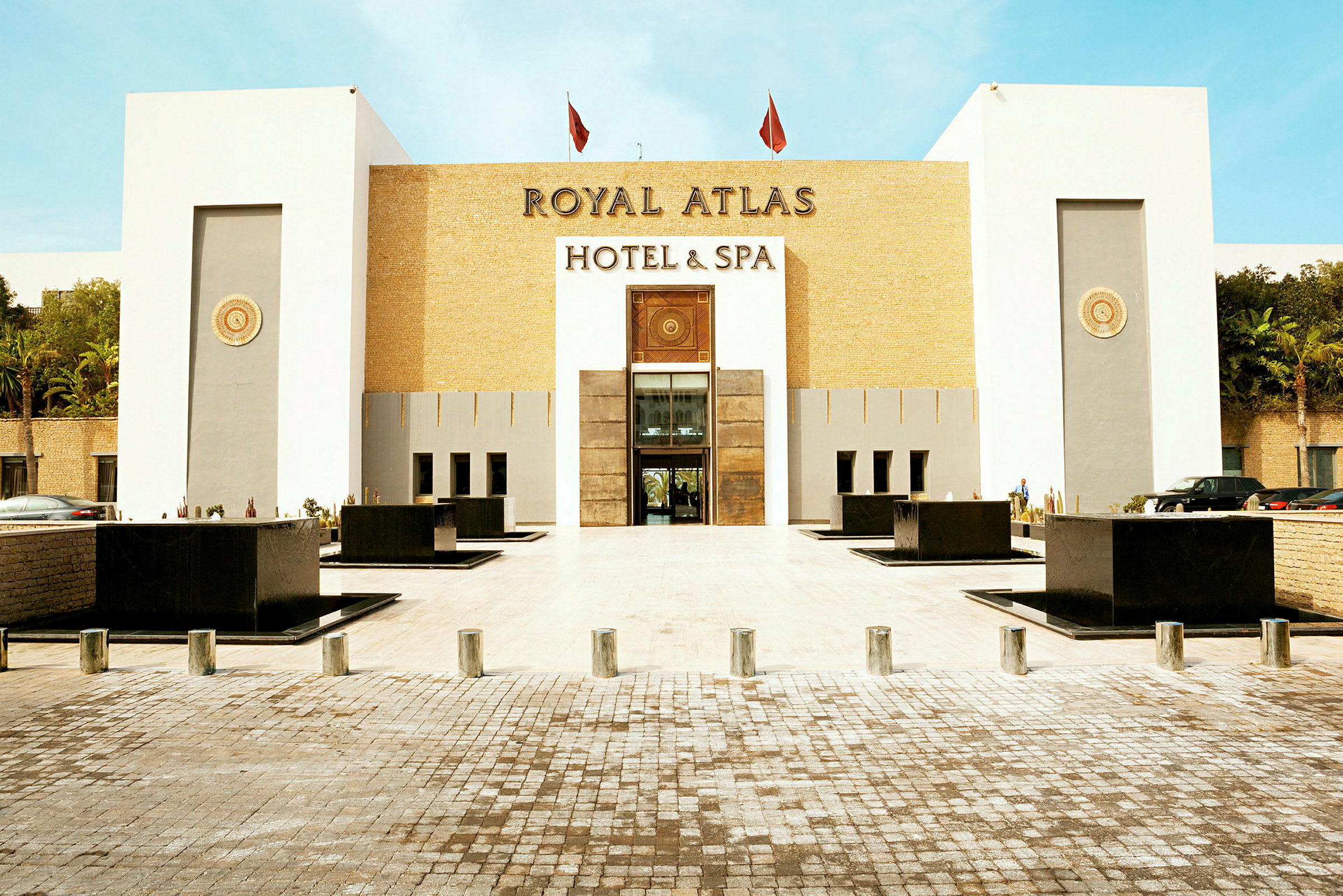 Framsidan av ett hotell som heter Royal Atlas Hotel & Spa, med en modern och stilren fasad. (AI-genererad text)
