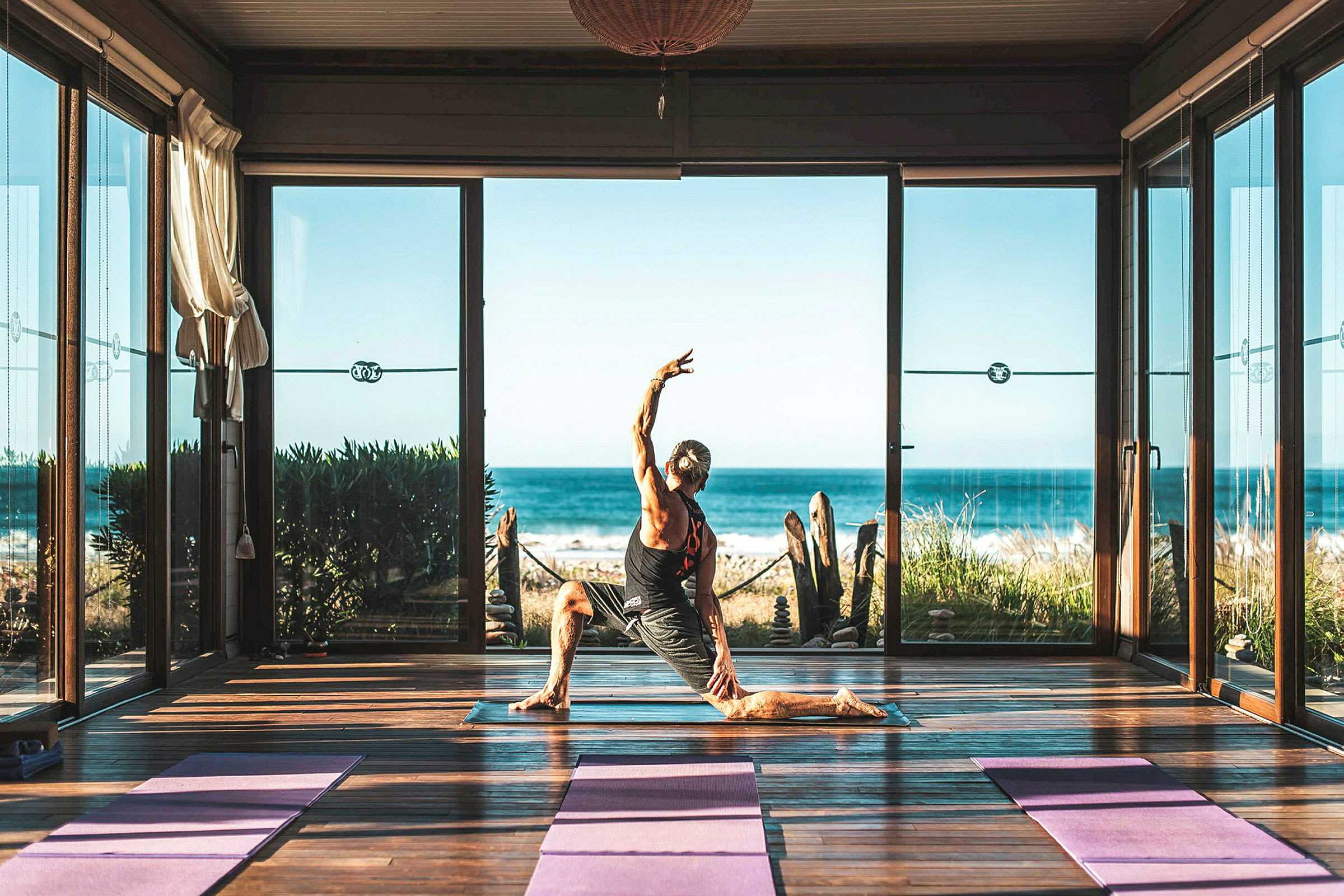 En person utför yoga i en ljus studio med utsikt över havet. (AI-genererad text)