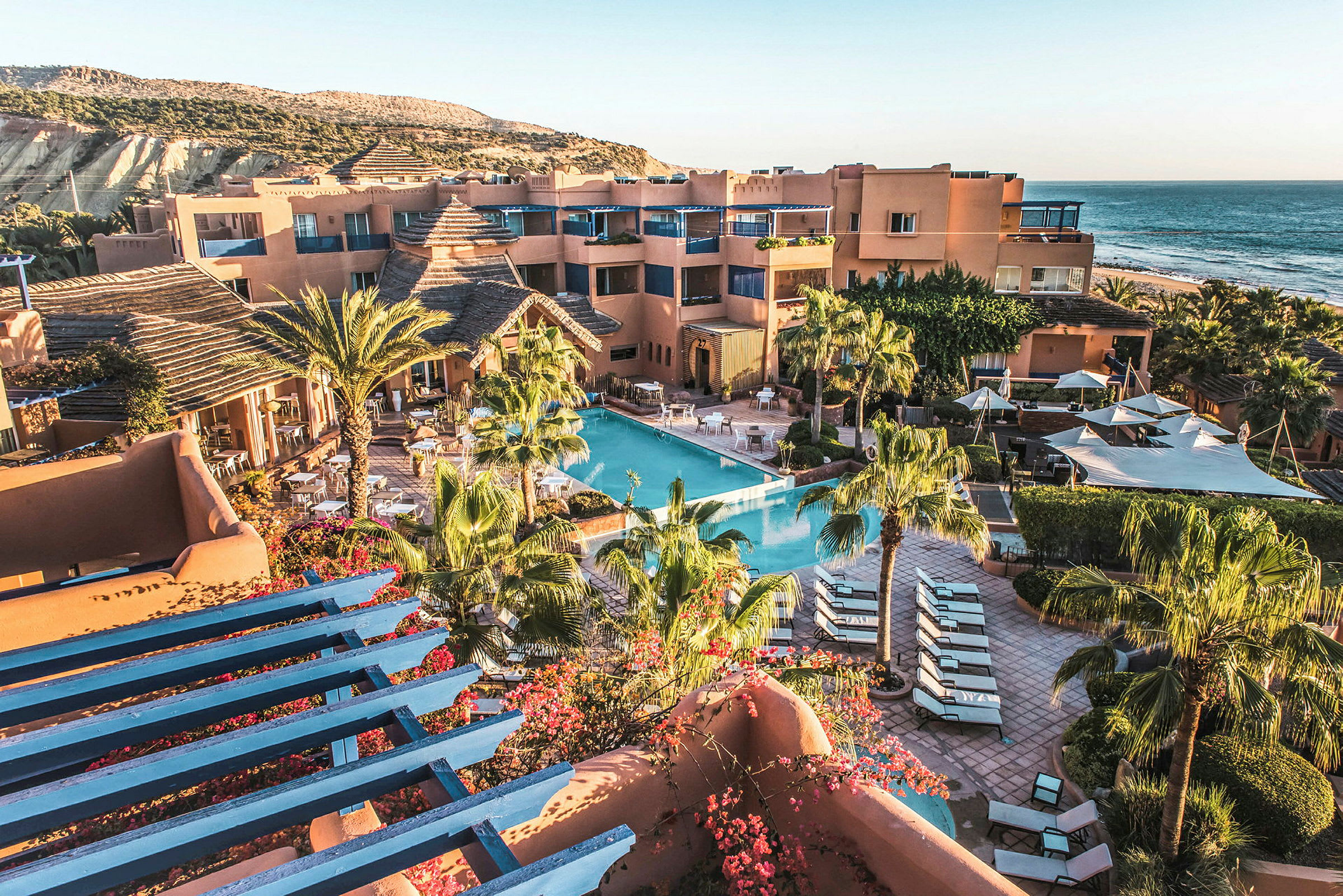 Ett soligt semesterrsort med pool, solstolar och omgivande växtlighet nära havet. (AI-genererad text)