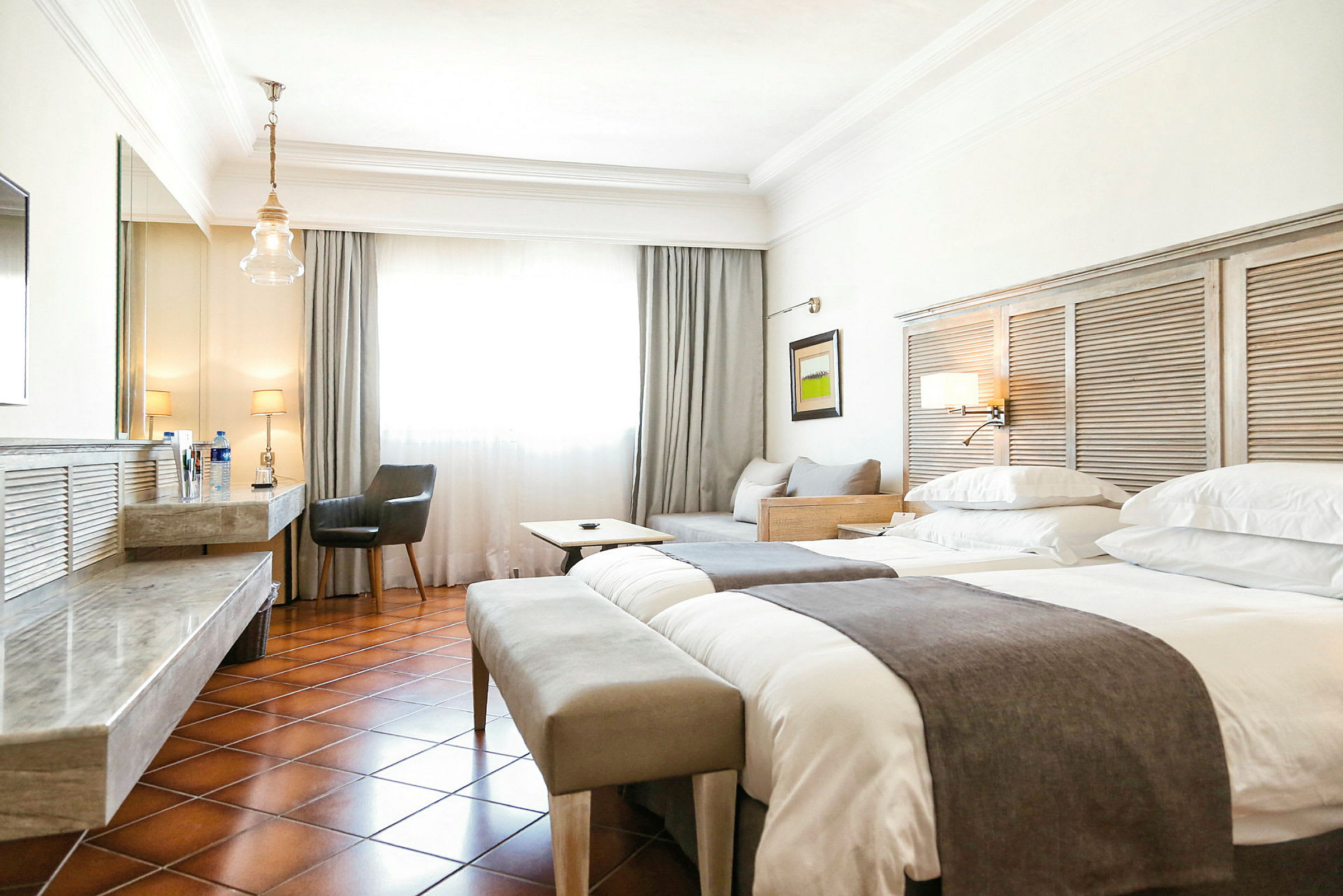 Hotellrum med två sängar, sittmöbler och skrivbord. (AI-genererad text)