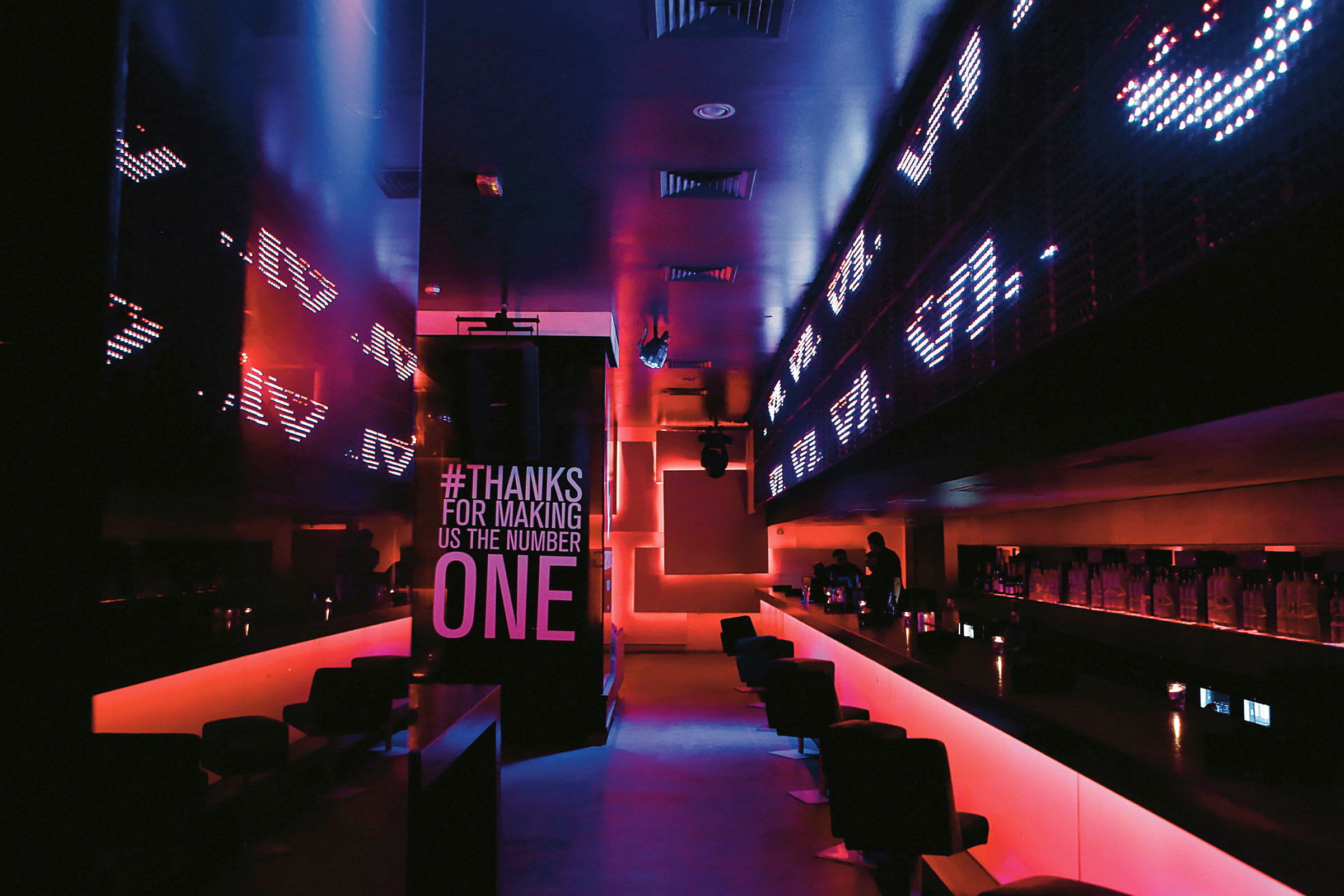 Bild på en modernt designad bar med neonbelysning och LED-skärmar. (AI-genererad text)