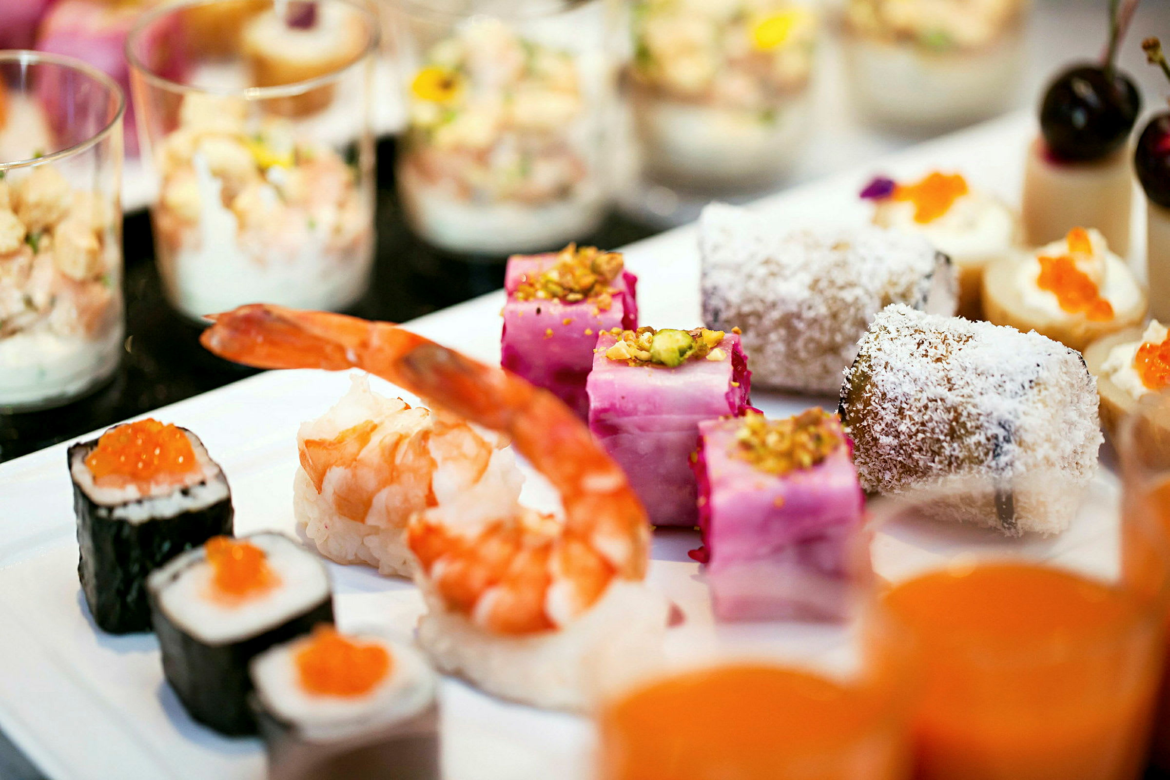 Olika typer av delikata smårätter på ett fat, inklusive sushi, räkor och desserter. (AI-genererad text)