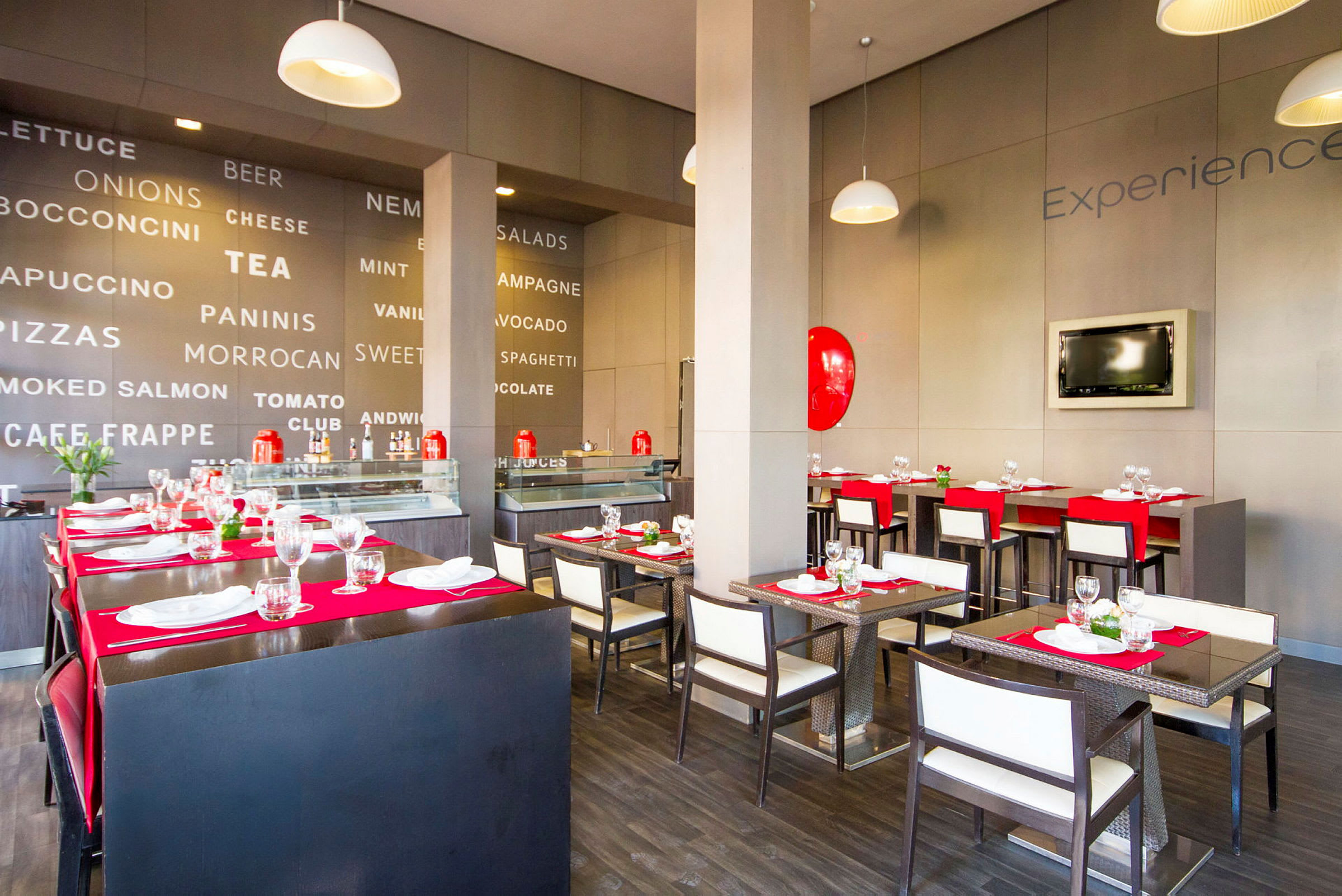 En modern restaurang med elegant inredning, bord dukade med röda underlägg och vita servetter. Väggarna är dekorerade med stora ord som relaterar till mat och dryck. (AI-genererad text)