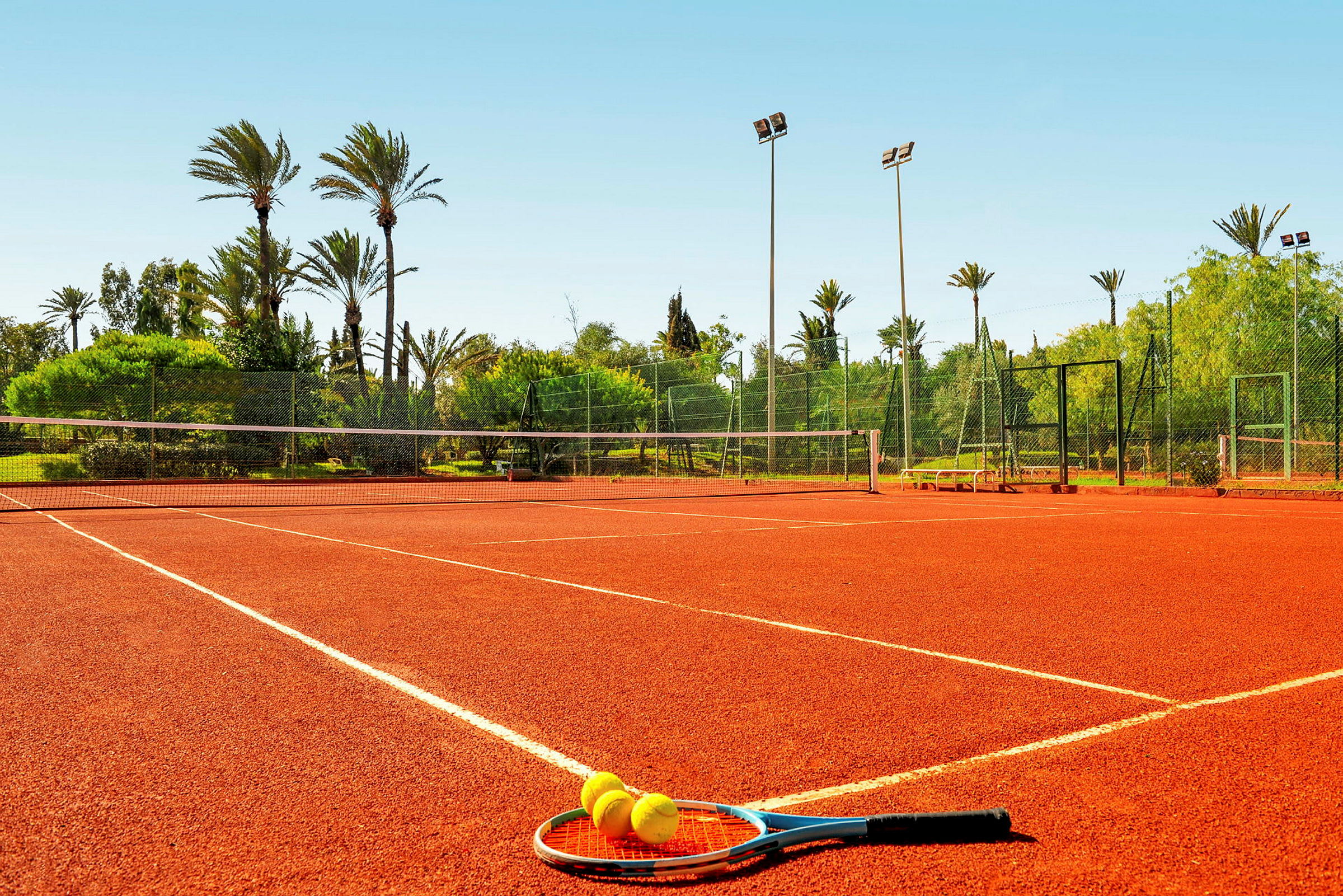 Tennisbana med racket och bollar på marken. (AI-genererad text)