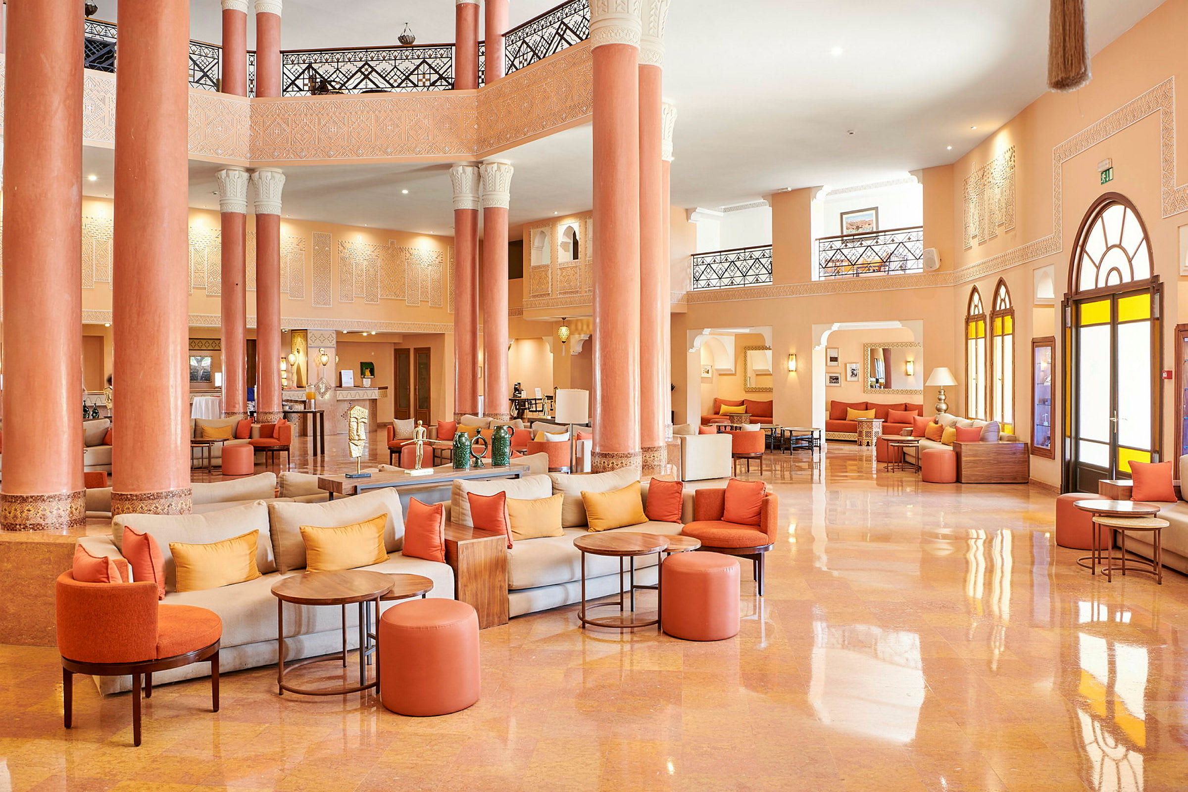 Hotellobby med orange och beige färger, sittgrupper och pelare. (AI-genererad text)