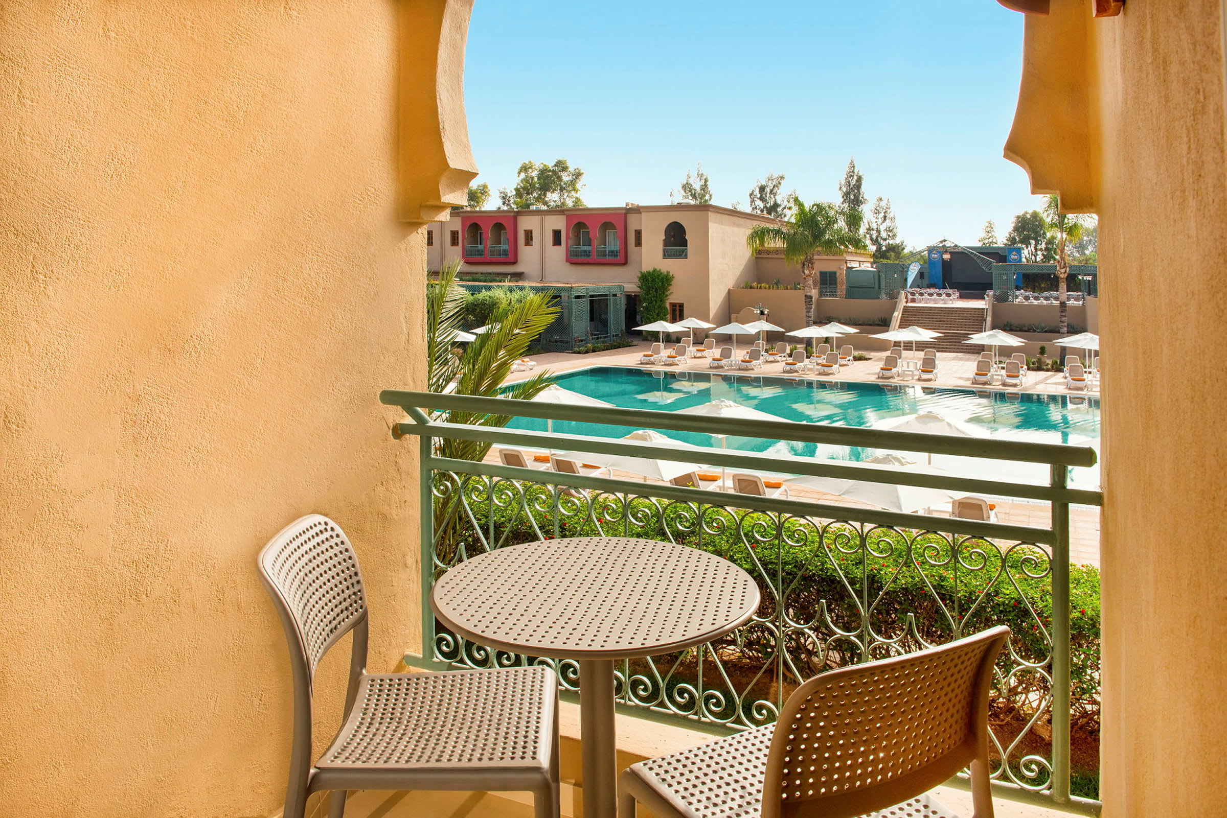 En balkong med utsikt över en pool och solstolar. (AI-genererad text)