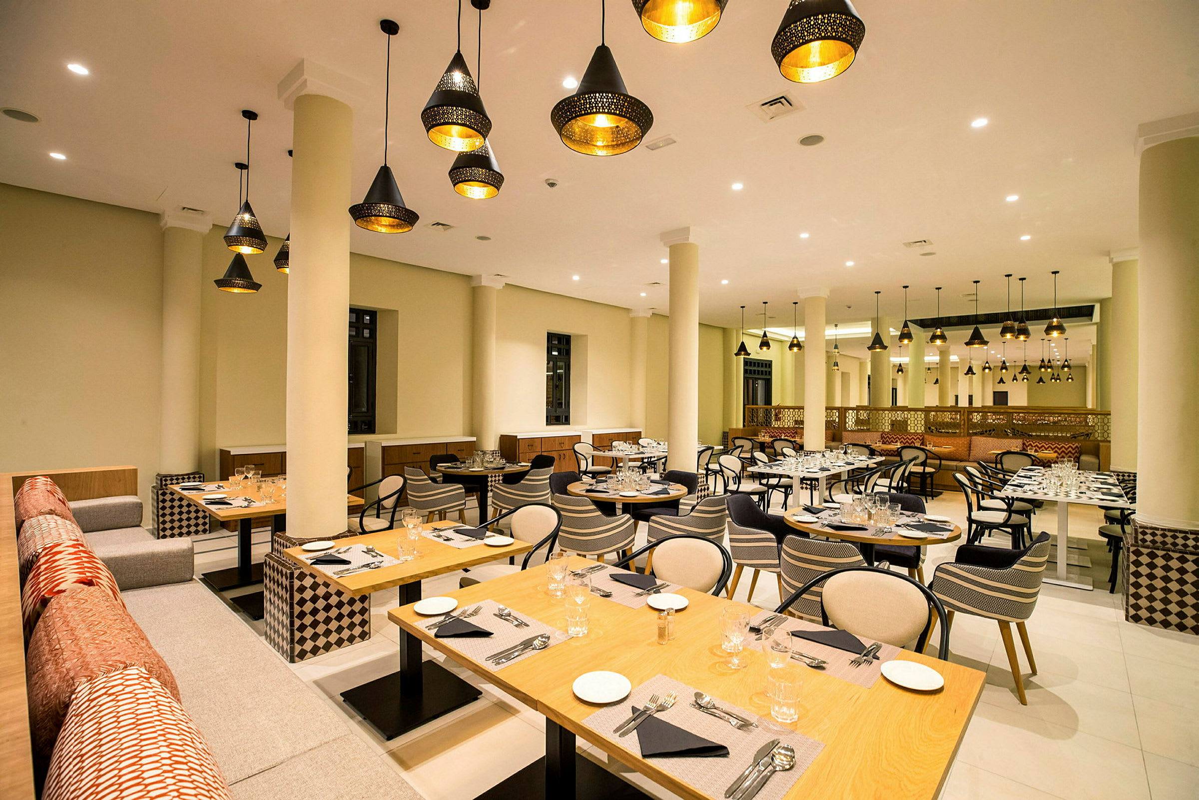 Restaurang med dekorativa lampor, dukade bord och sittplatser. (AI-genererad text)
