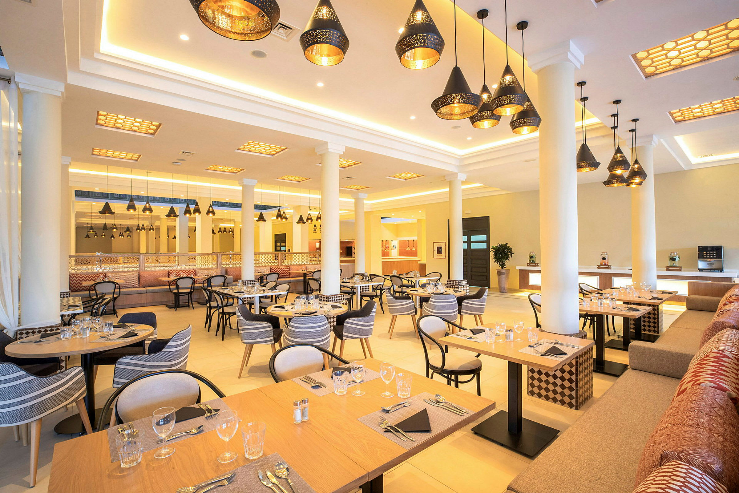 Restaurang med dukade bord och hängande taklampor. (AI-genererad text)